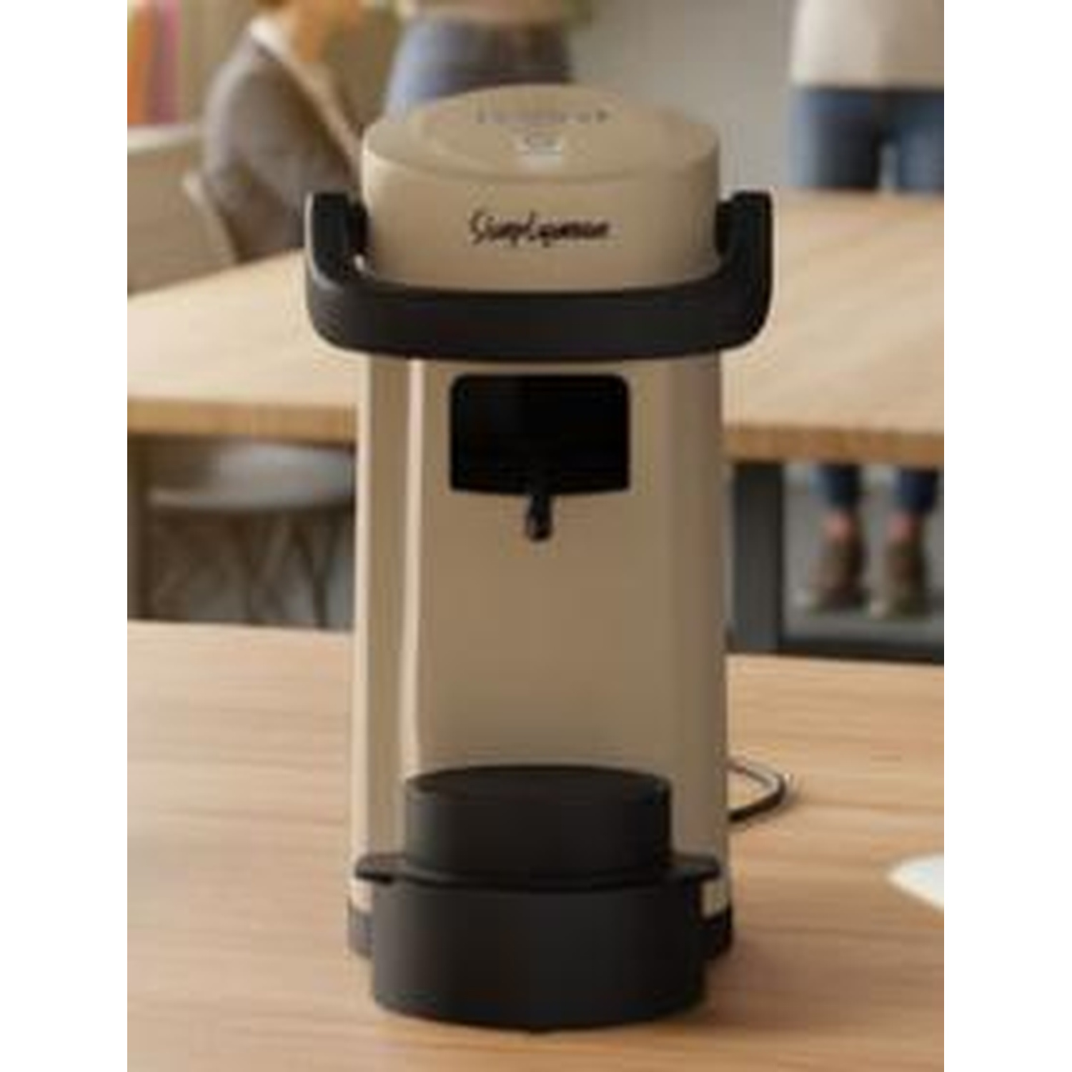 Una macchina da caffè beige con manico nero siede su un tavolo di legno.