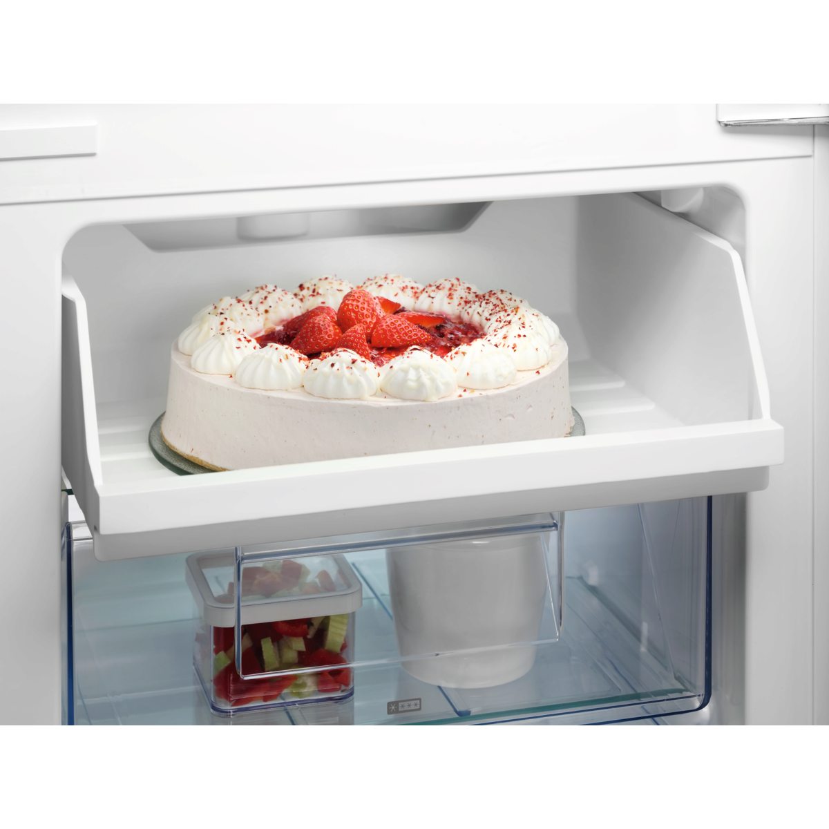 Kerek torta eperrel és tejszínhabbal a hűtőpolcon.