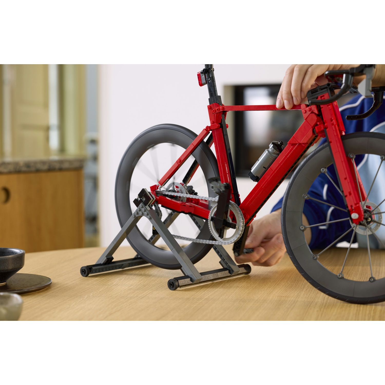 Una bicicletta Lego rossa è su un supporto su un tavolo di legno.