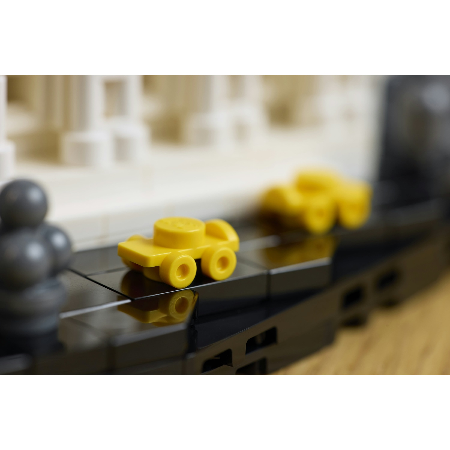 Una macchina Lego gialla su una superficie Lego nera con sfondo sfocato.
