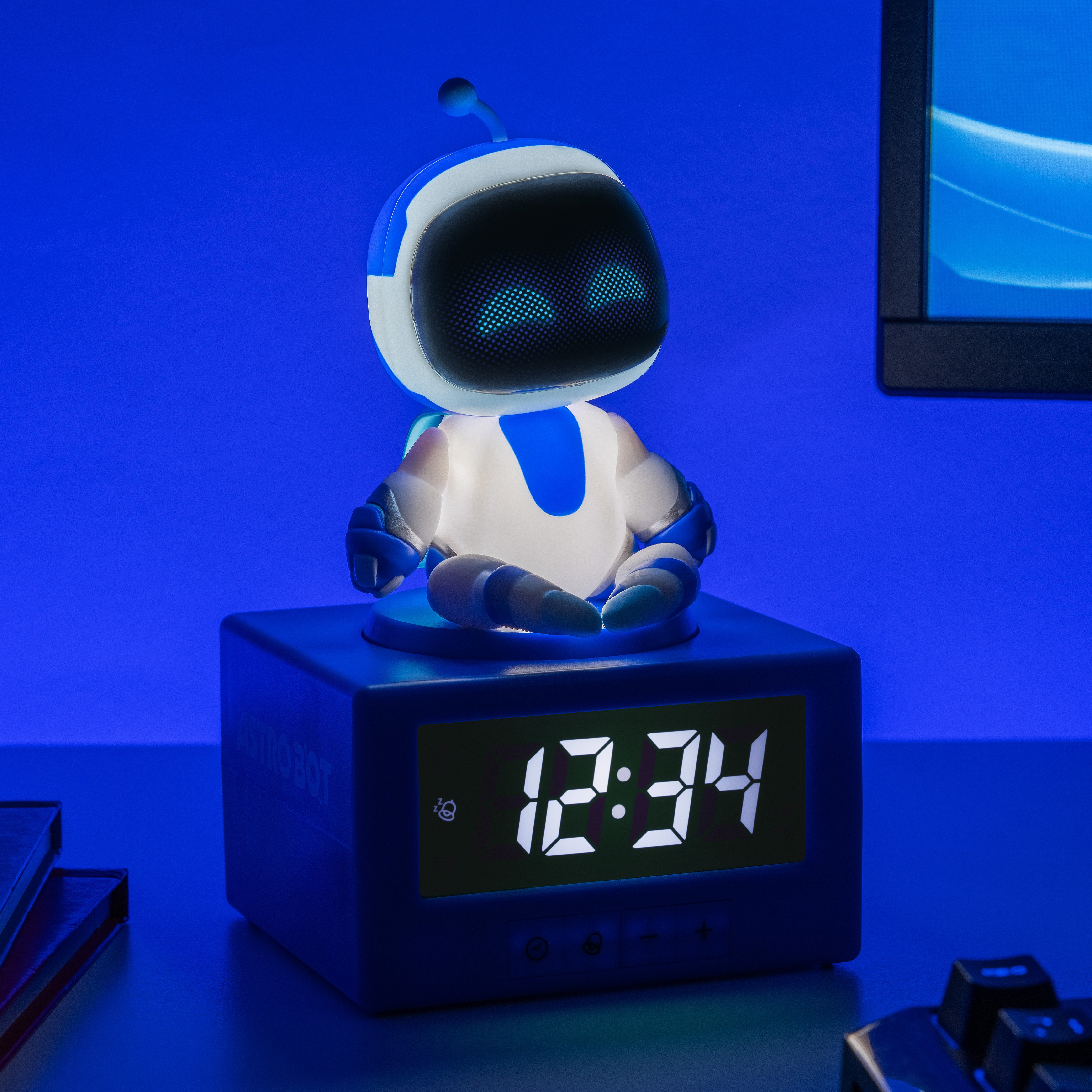 Ein beleuchteter Astro Bot sitzt auf einem blauen Wecker, der 12:34 anzeigt.