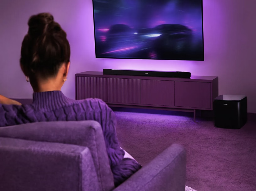Lila pulóveres nő neon lila megvilágítású TV-t néz.