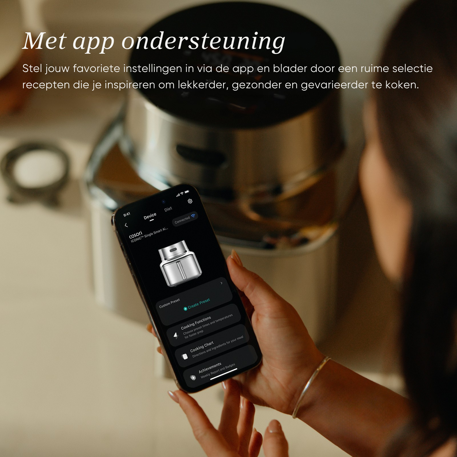 A hand holds a smartphone displaying an app controlling a cooking device.