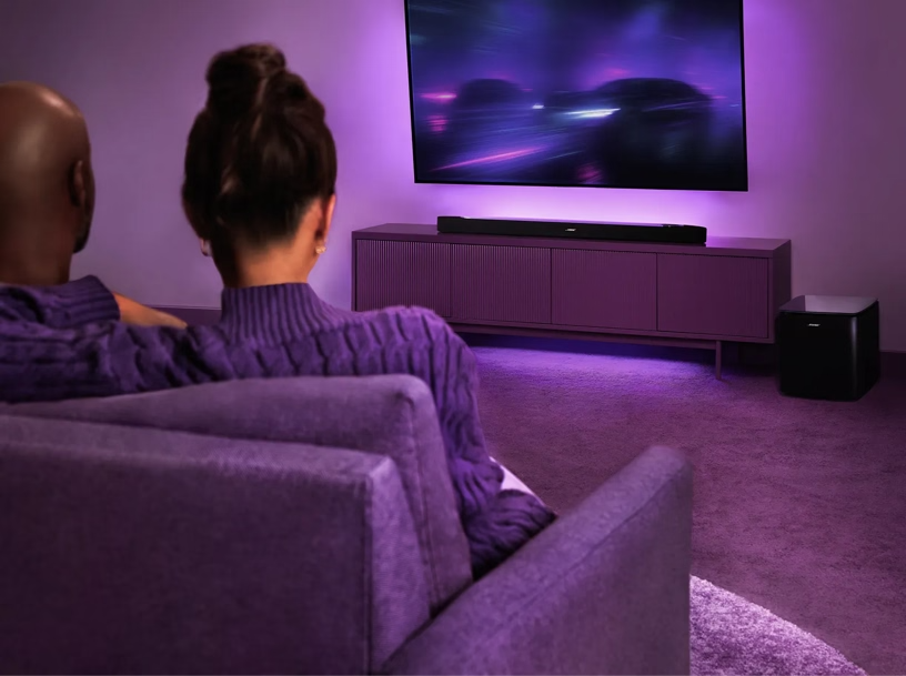 Egy pár filmet néz egy nagy TV-n, lila fényekkel megvilágítva.