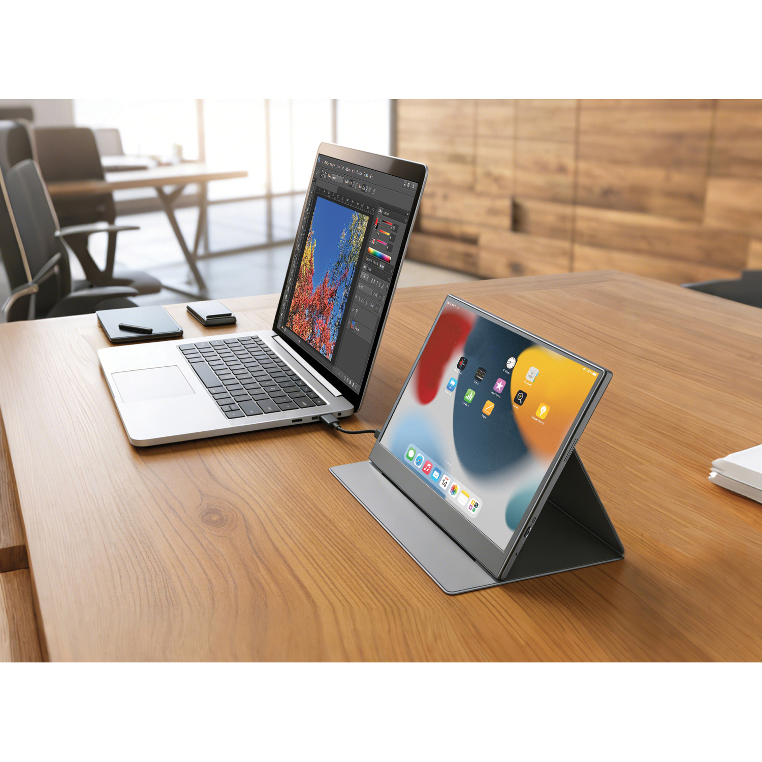 Un laptop e un monitor portatile su una scrivania di legno. Sedie da ufficio e pareti in legno sullo sfondo.