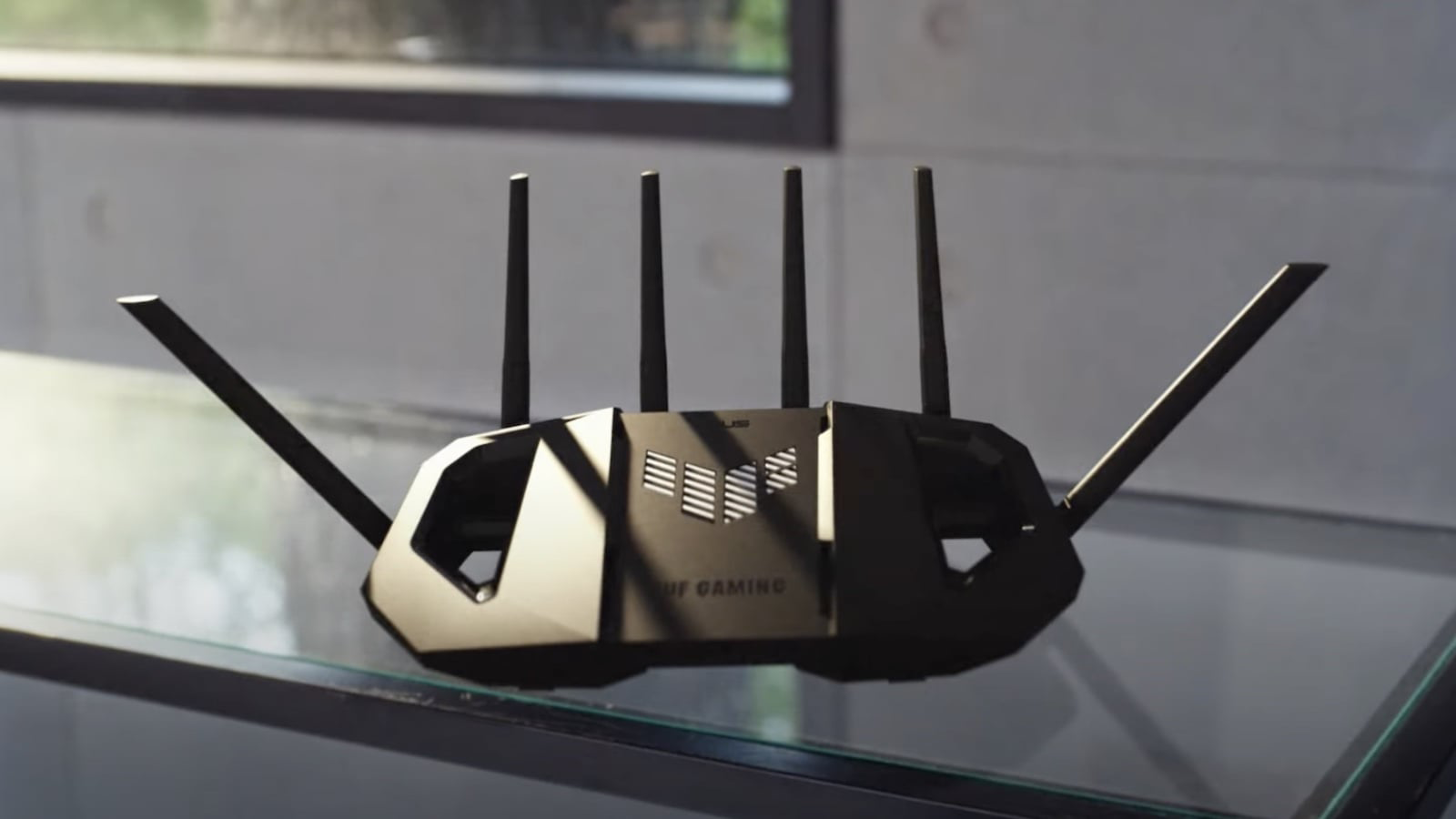 Egy fekete, négy antennás router üveglapon áll.