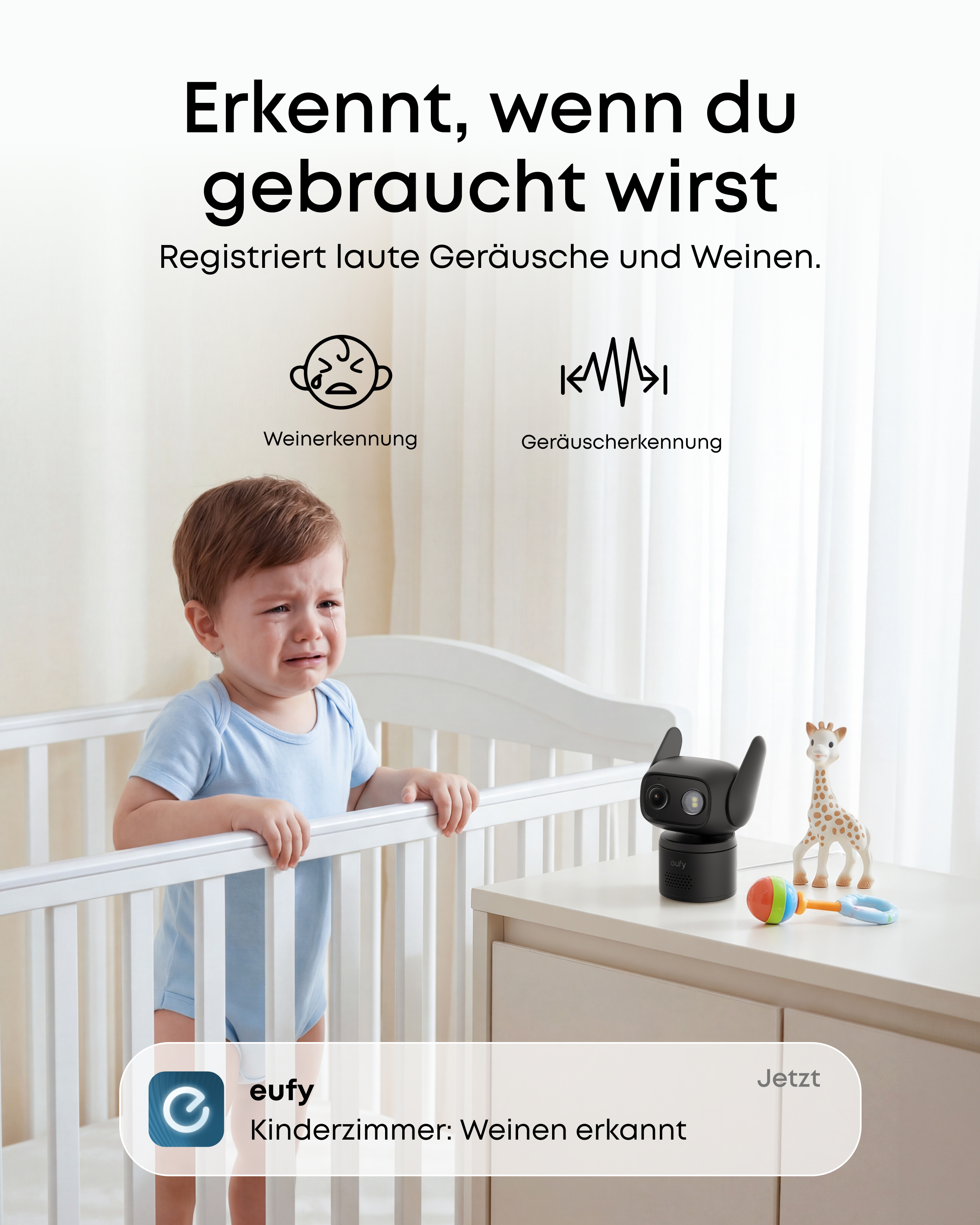 Ein weinendes Baby im Kinderbett neben einem Babyphone und Spielzeug.