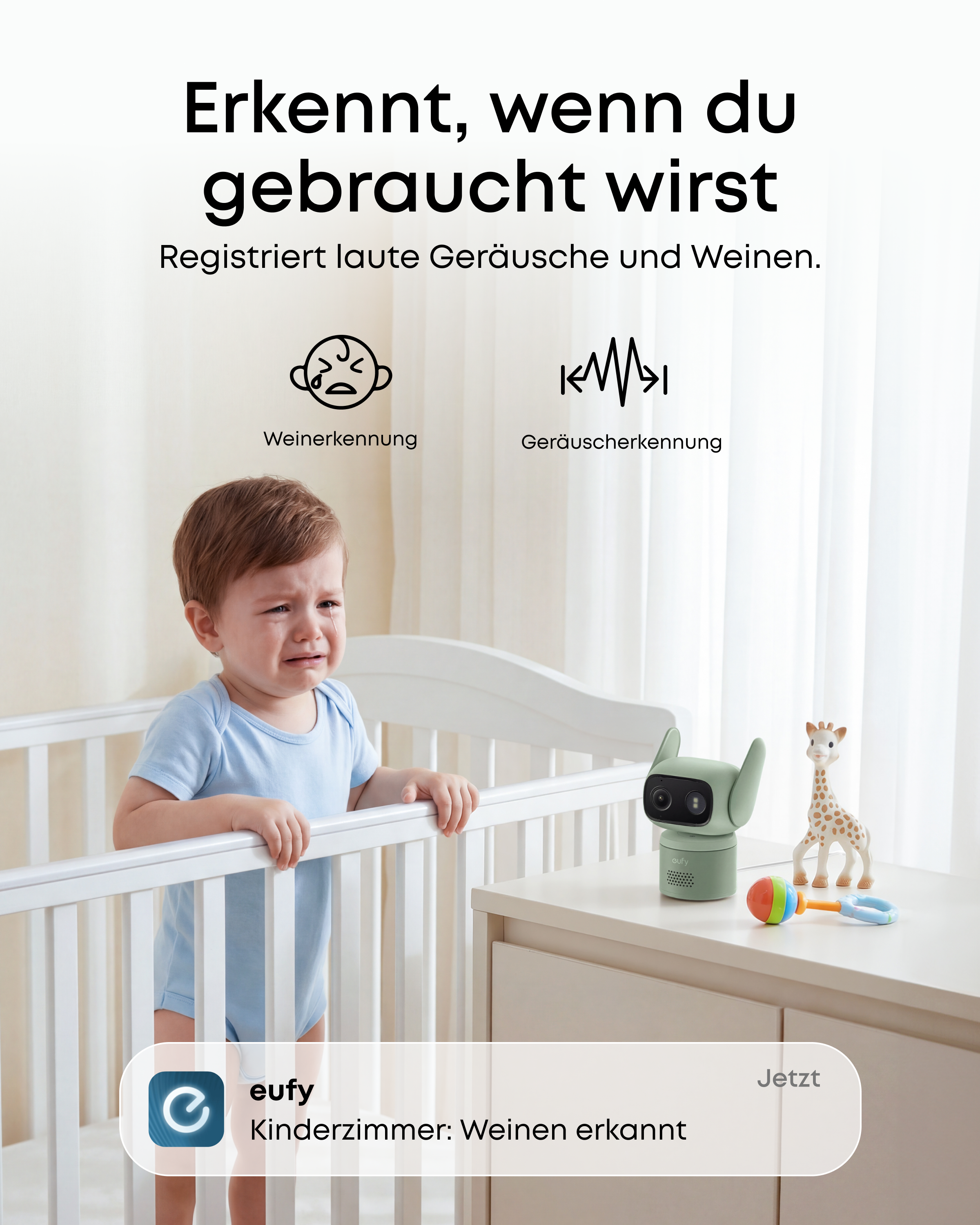 Ein weinendes Baby in einem Gitterbett neben einem Babyphone und Spielzeug.