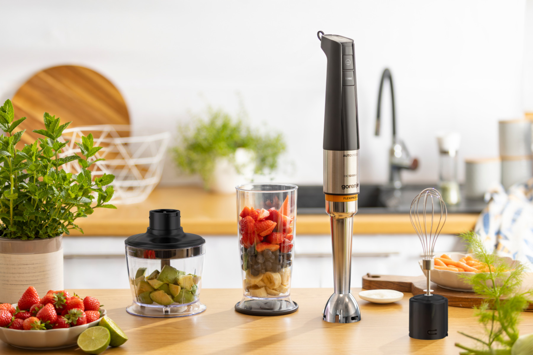 Blender ręczny z akcesoriami, owocami i warzywami na drewnianej powierzchni.