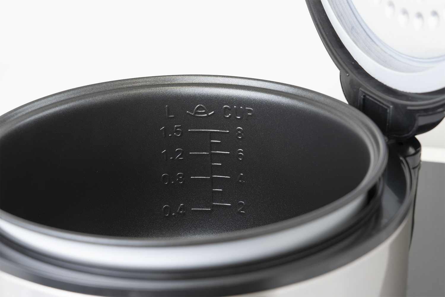 Vista interior de una arrocera abierta con marcas de medición en litros y tazas.