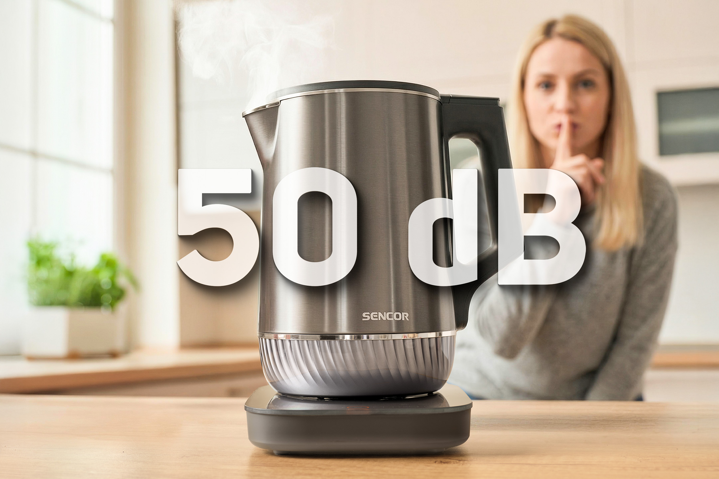Egy SENCOR vízforraló 50 dB zajszinttel, mellette egy nő, aki csendre int.