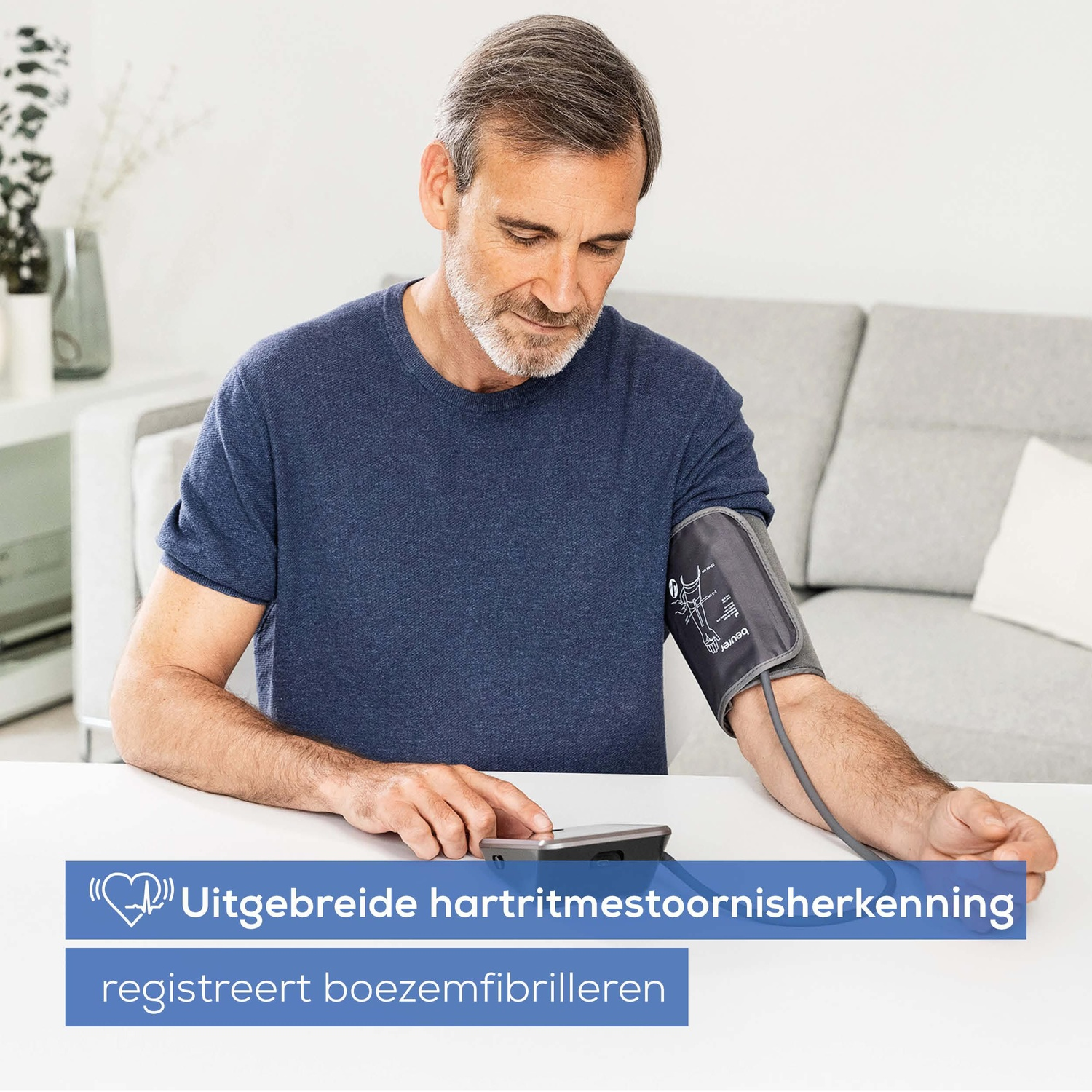 Man uses a blood pressure monitor. Upper arm cuff and display are visible.