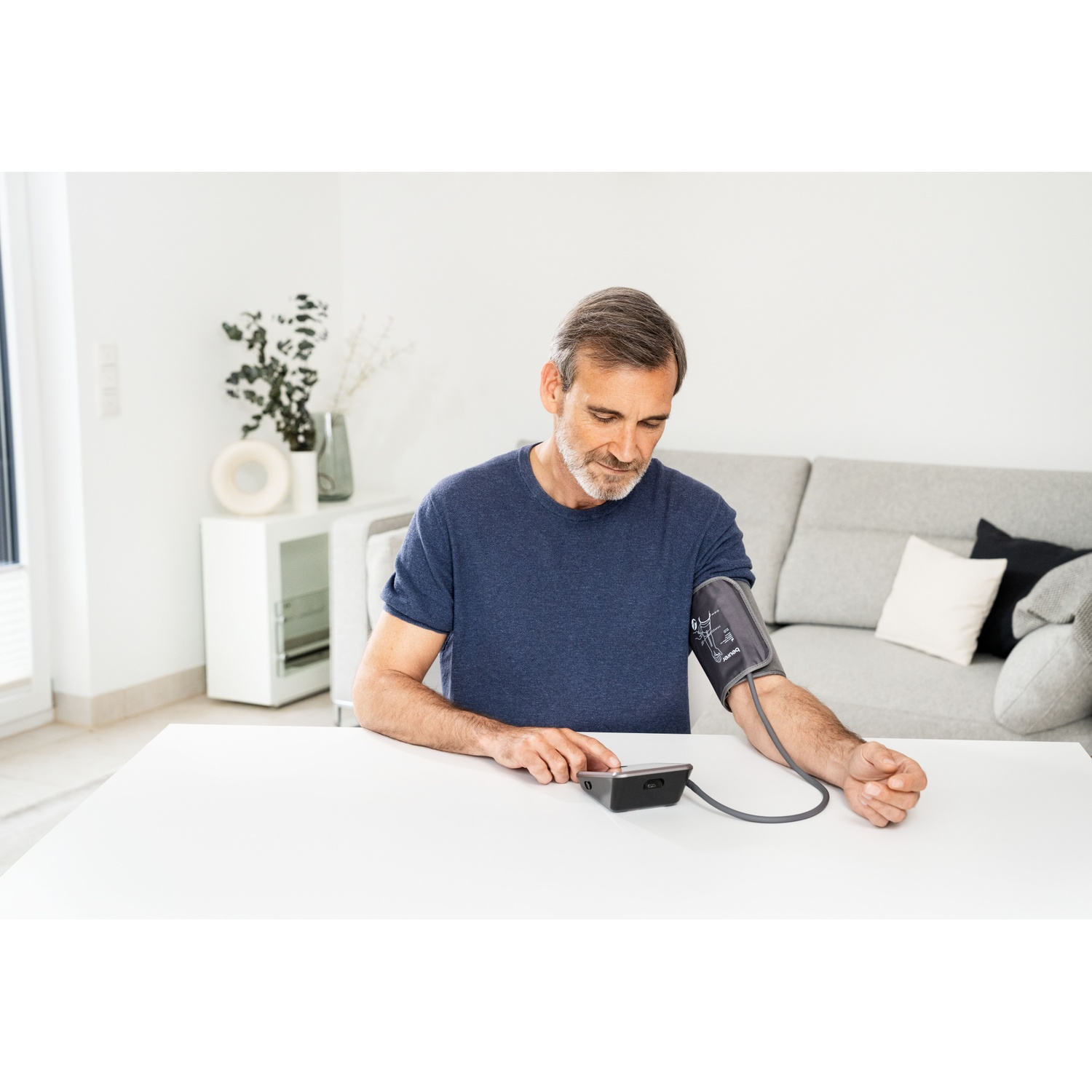 Man measures blood pressure with device at table