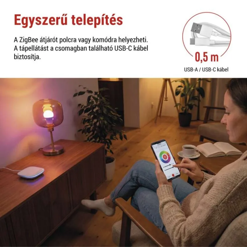 Egy nő okostelefonnal vezérel egy lámpát. Közelben Zigbee hub és USB kábel.