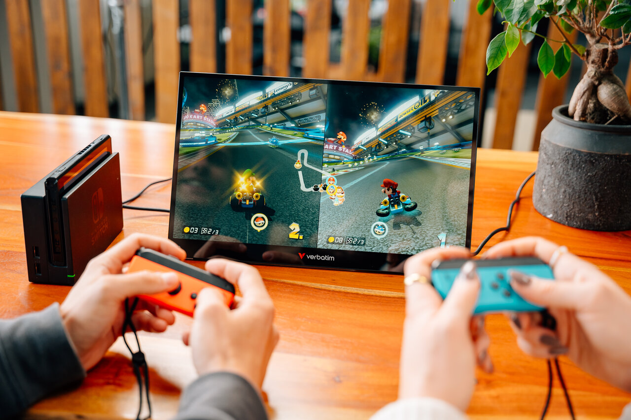 Due persone giocano a Mario Kart in split screen, tenuto da un Nintendo Switch.