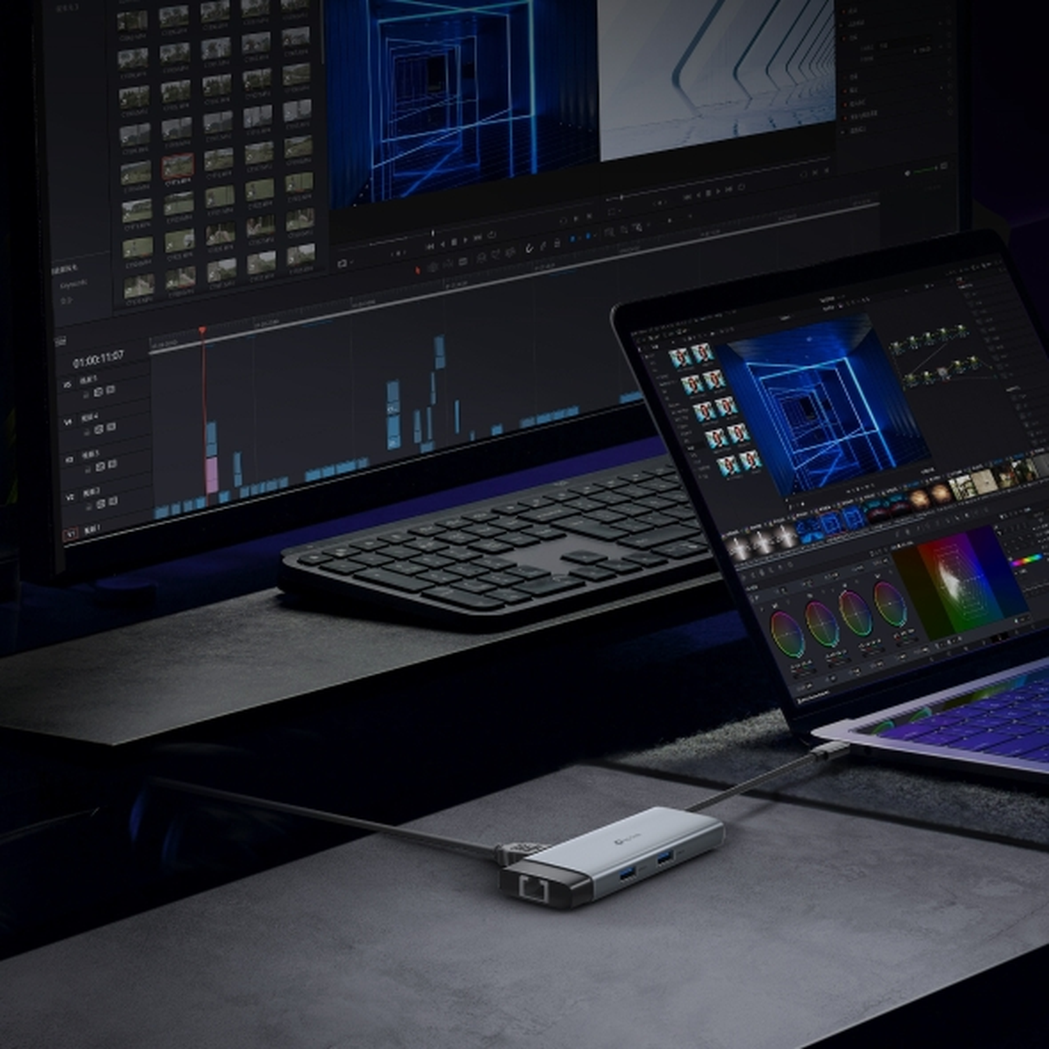 Een laptop en grote monitor tonen videobewerkingssoftware, verbonden via een hub.