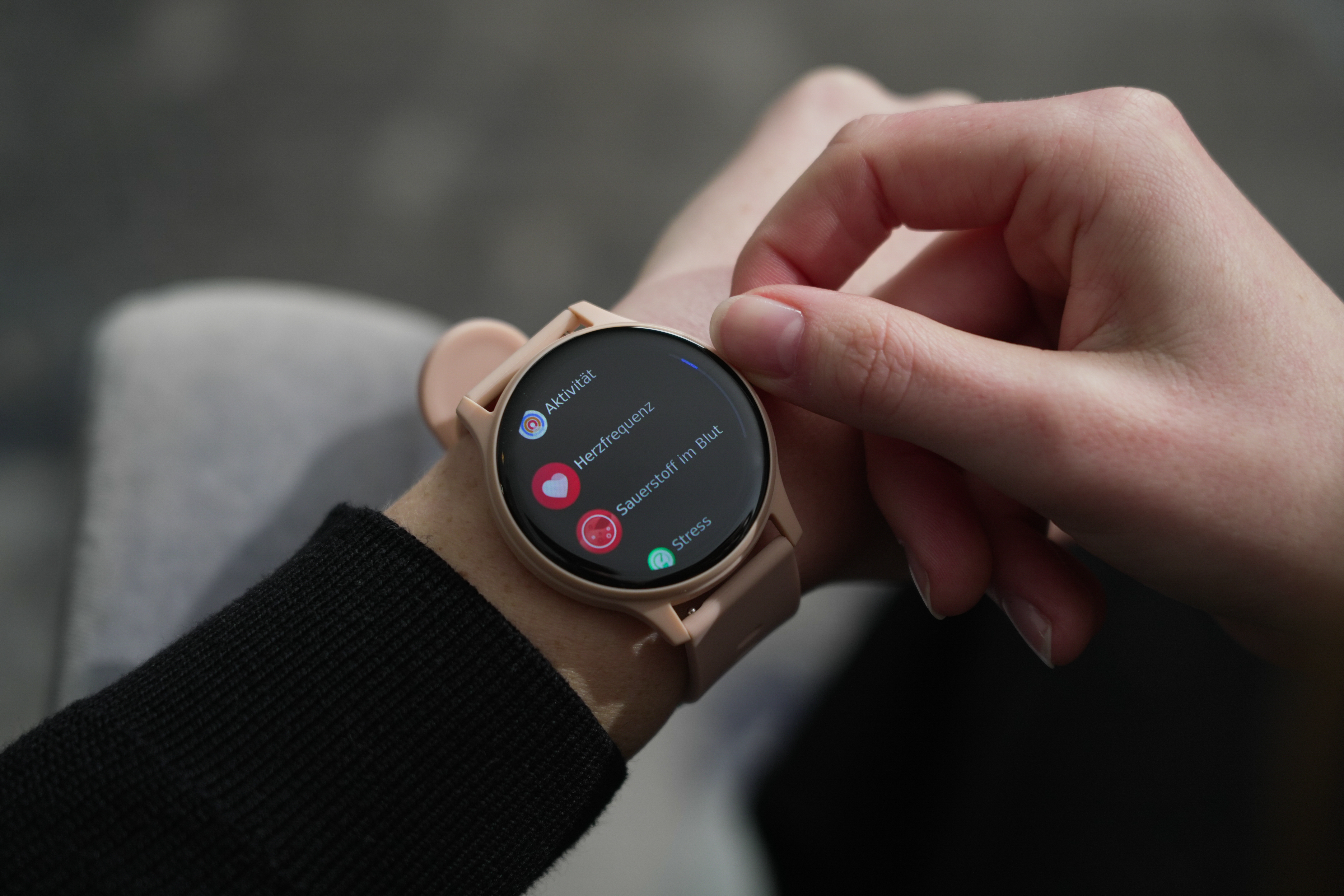 Il polso di una persona indossa uno smartwatch rosa che mostra metriche di salute come attività e stress.