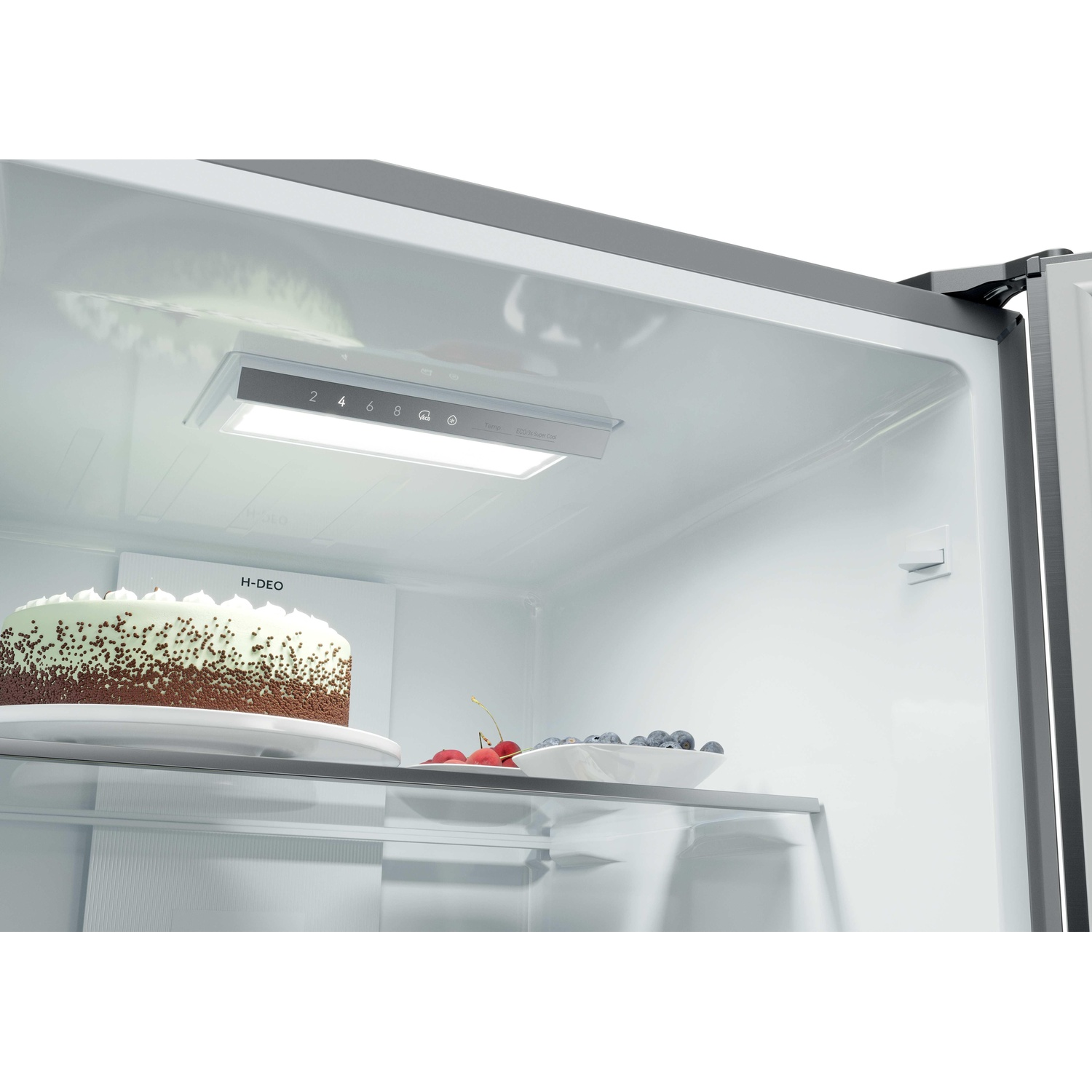 All'interno di un frigorifero, una torta e bacche su ripiani con illuminazione interna e controlli.