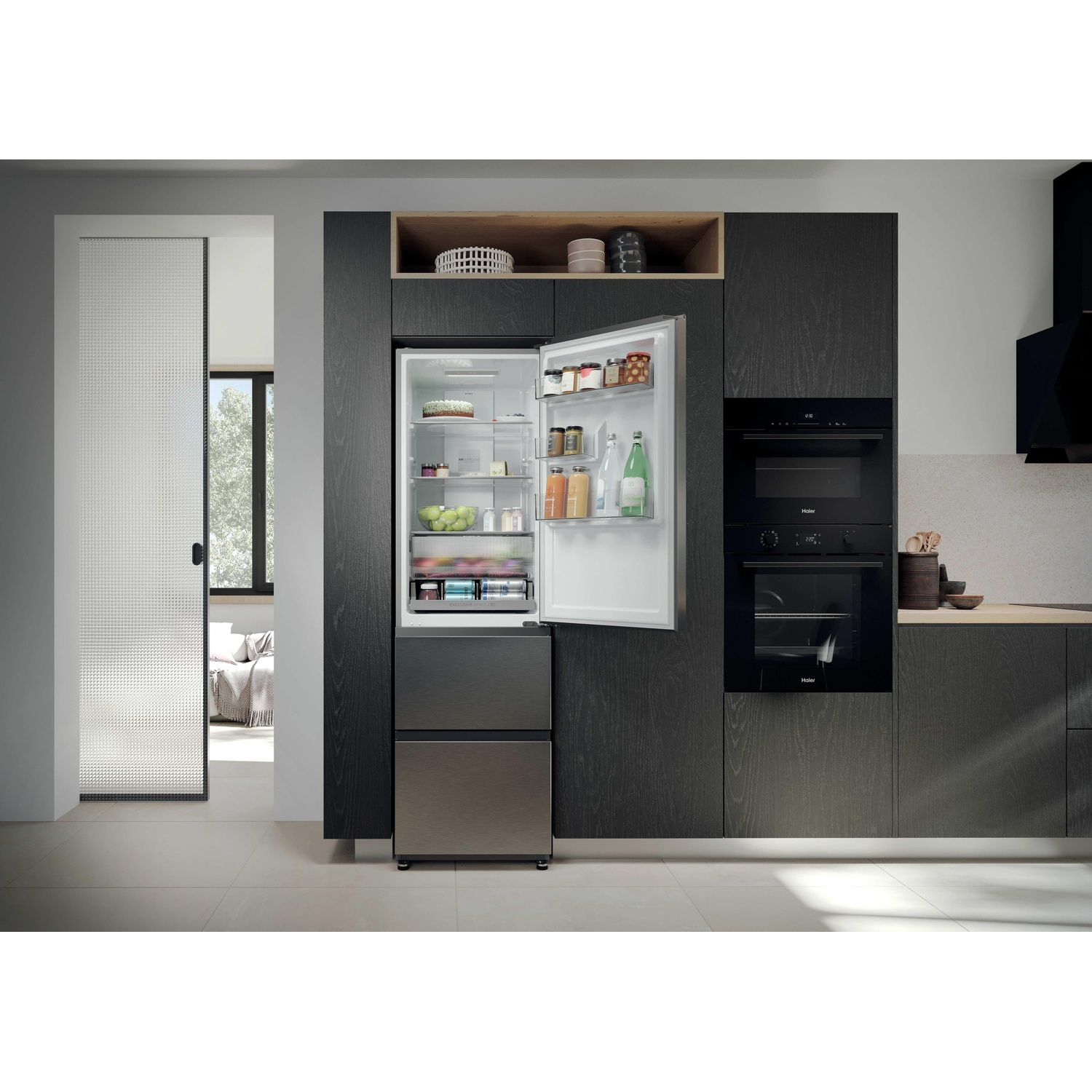 Un frigorifero aperto con cibo, accanto a un forno in una cucina moderna.