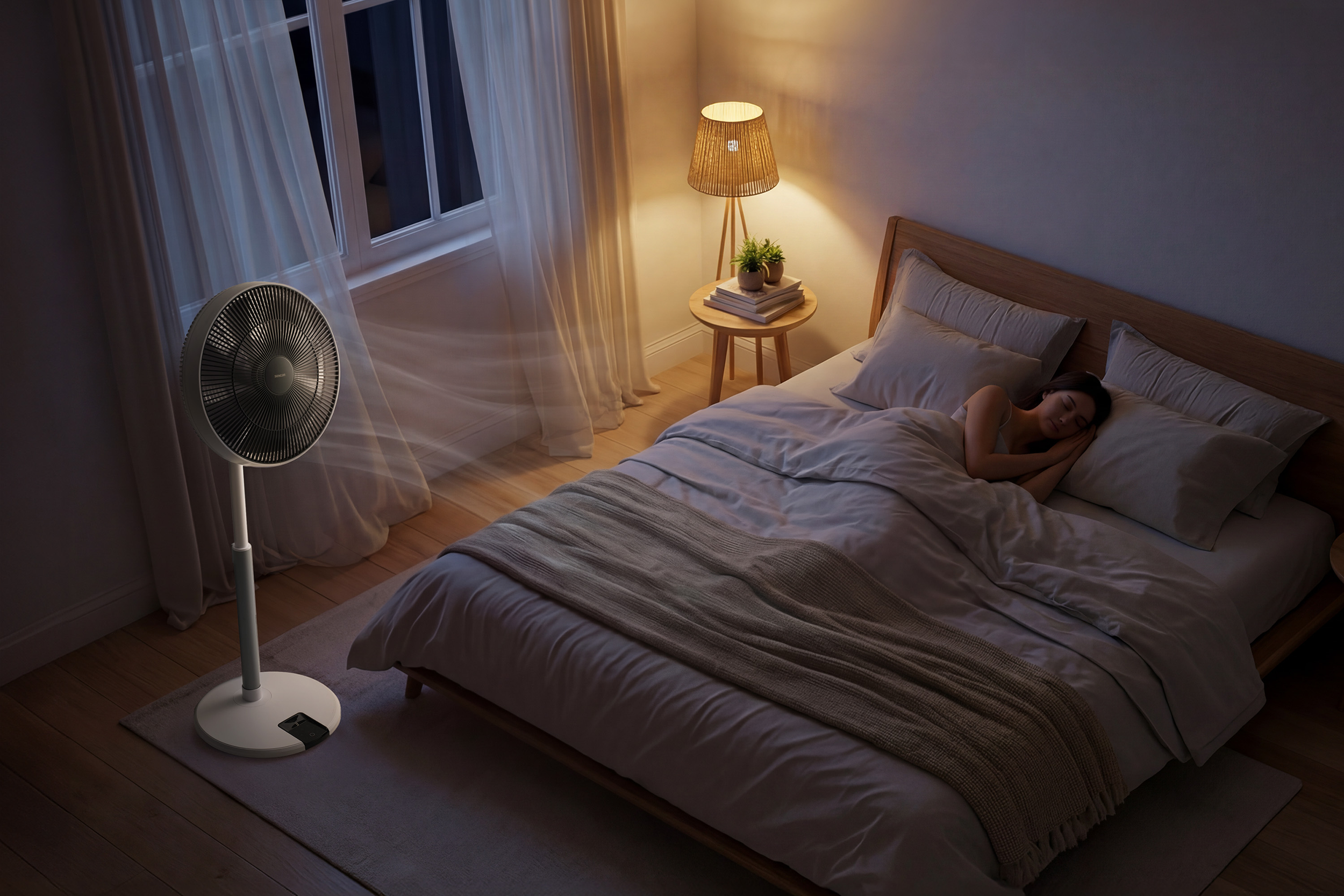 Egy nő alszik az ágyban, egy ventilátor fújja a levegőt.