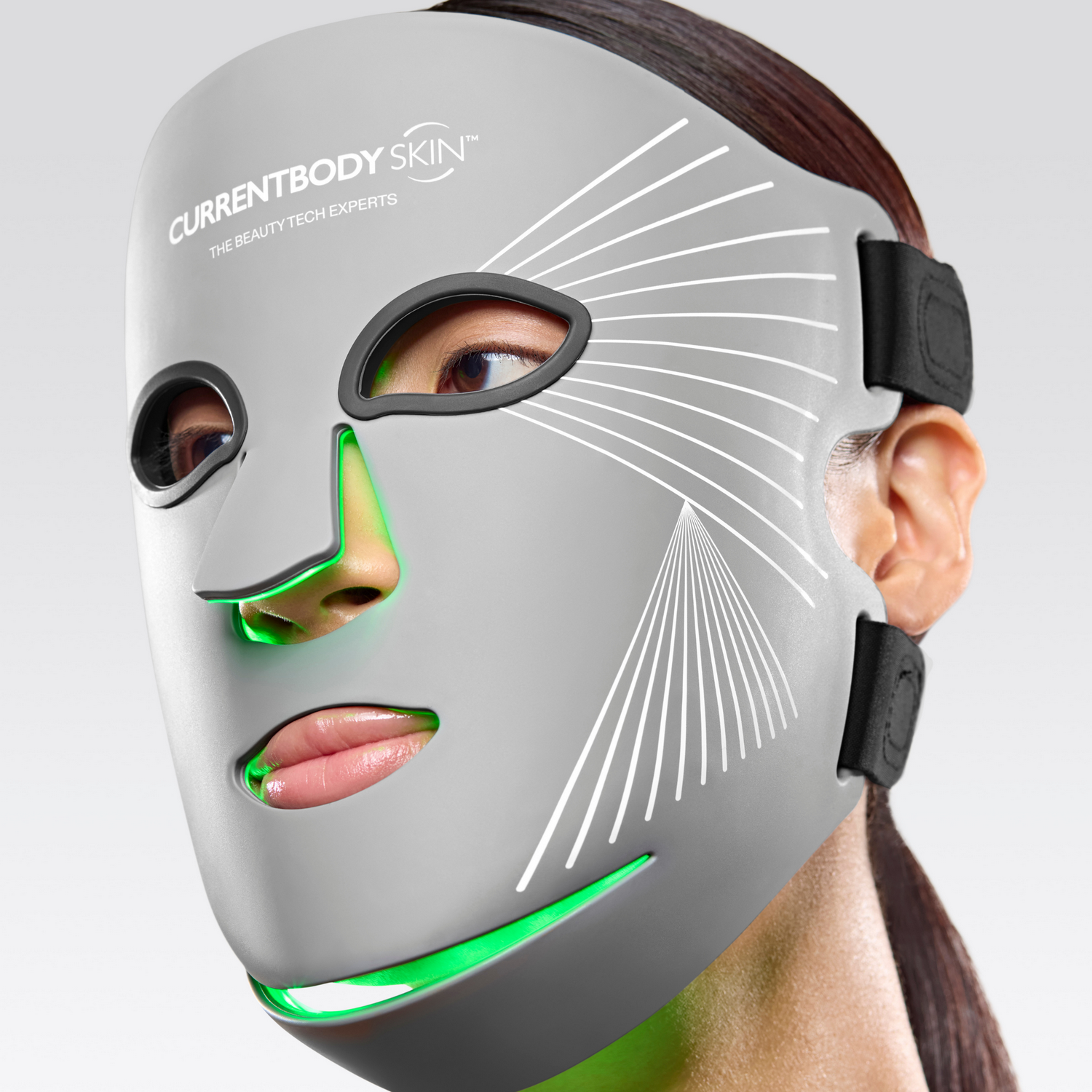 Una mujer usa una mascarilla facial LED gris con luces verdes.