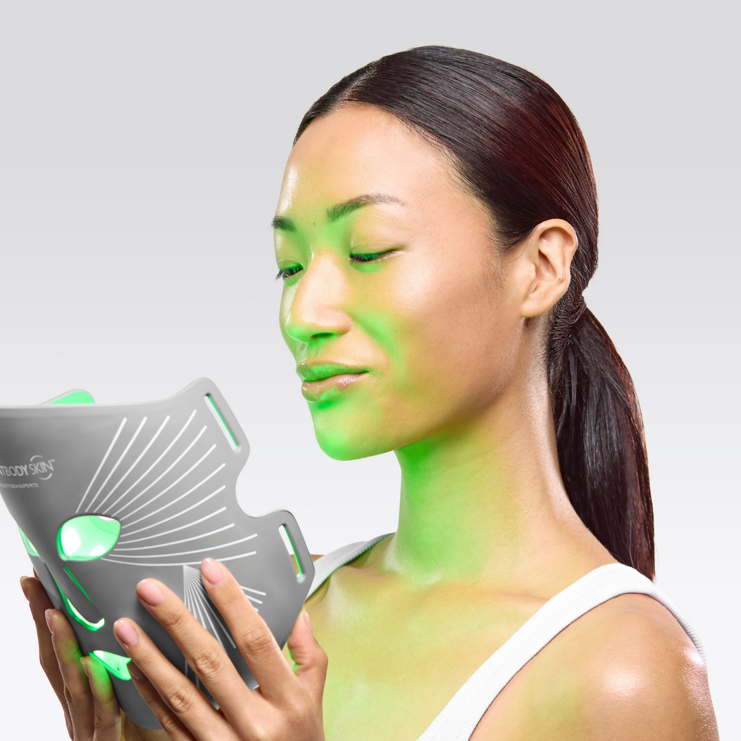 Una mujer sostiene una mascarilla gris con luces verdes.