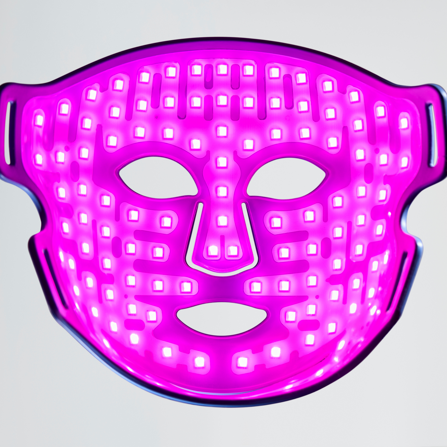Una mascarilla facial LED rosa brillante con aberturas para ojos y boca.