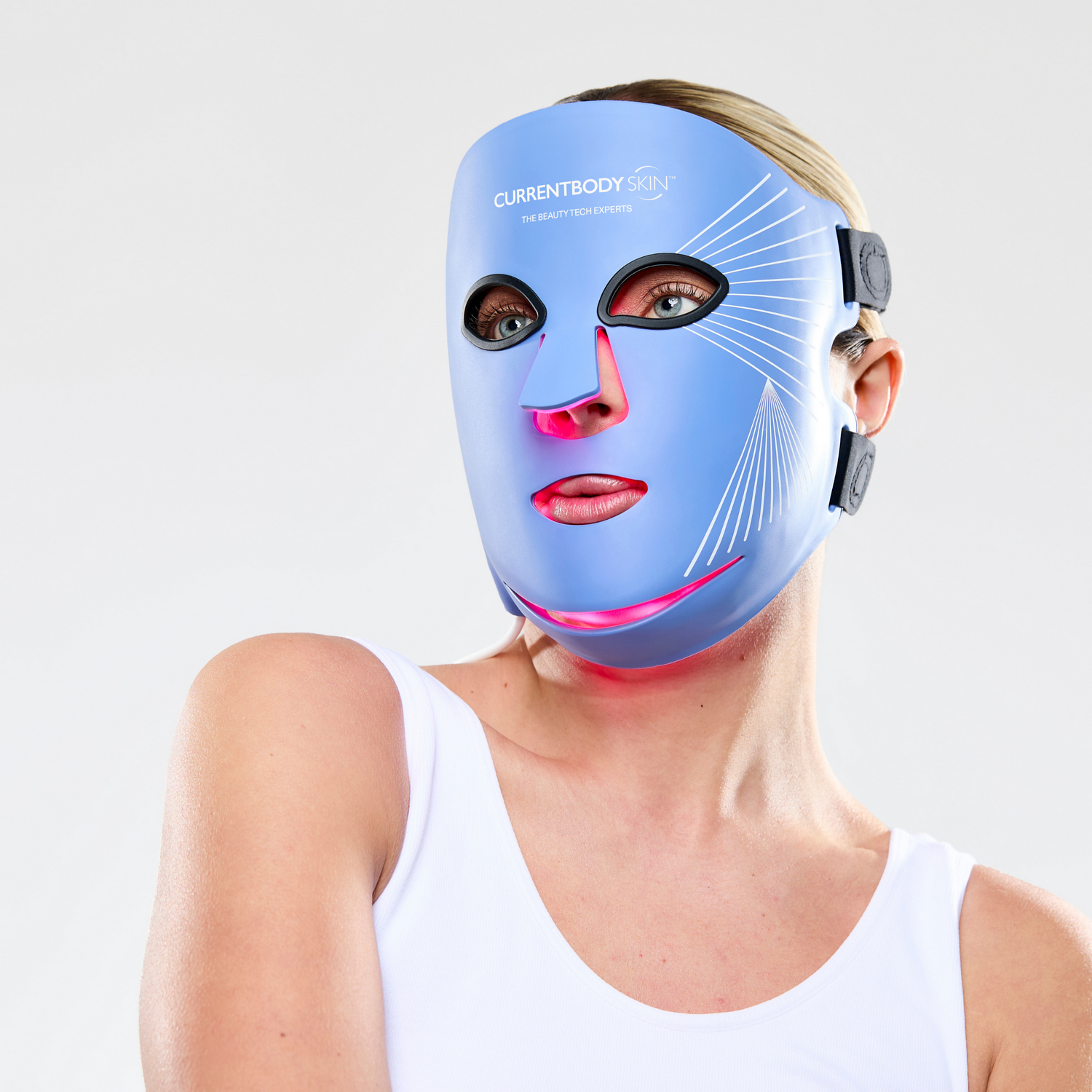 Una mujer usa una mascarilla facial LED azul con luces rojas debajo de los ojos.