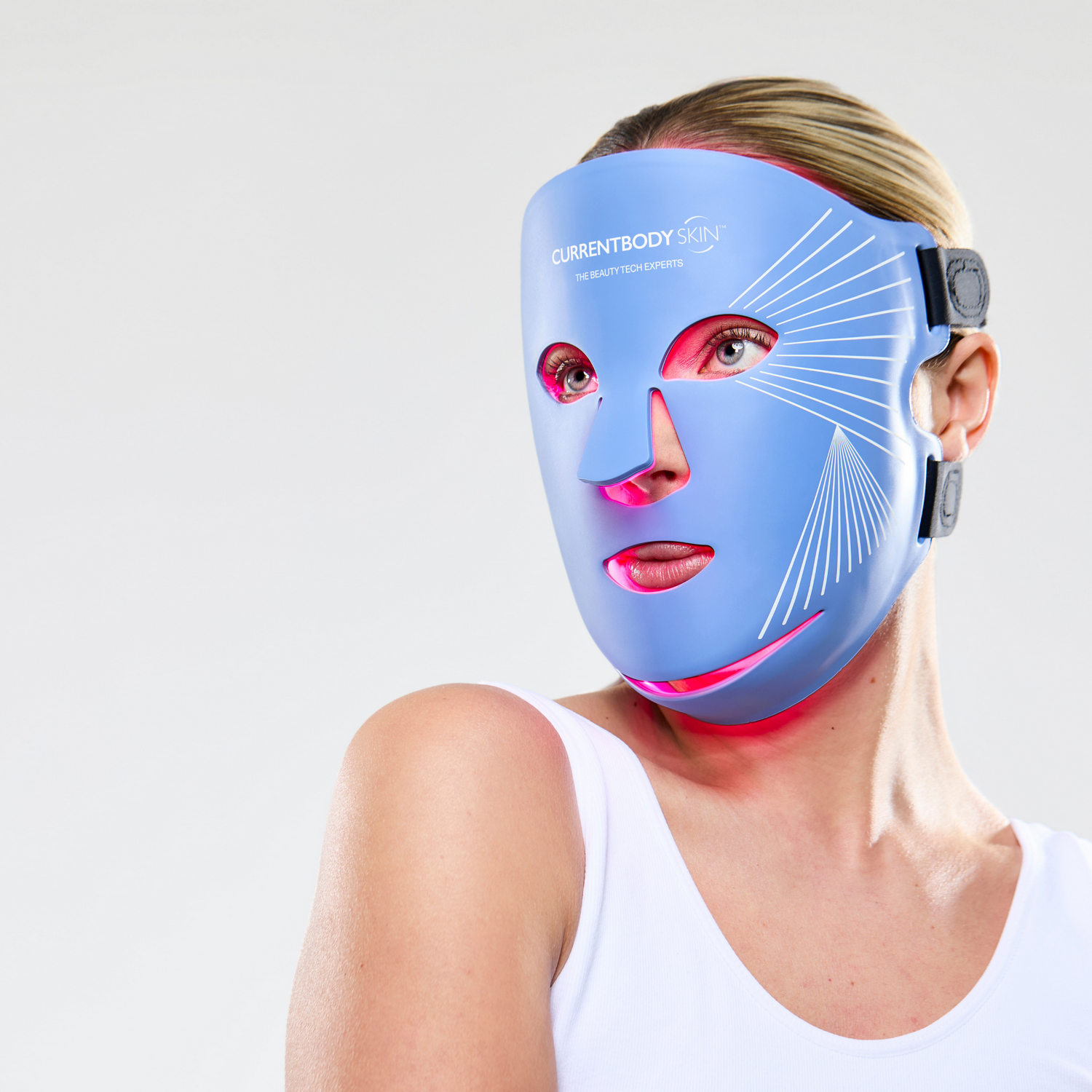 Una mujer lleva una mascarilla facial LED azul con luces rojas.