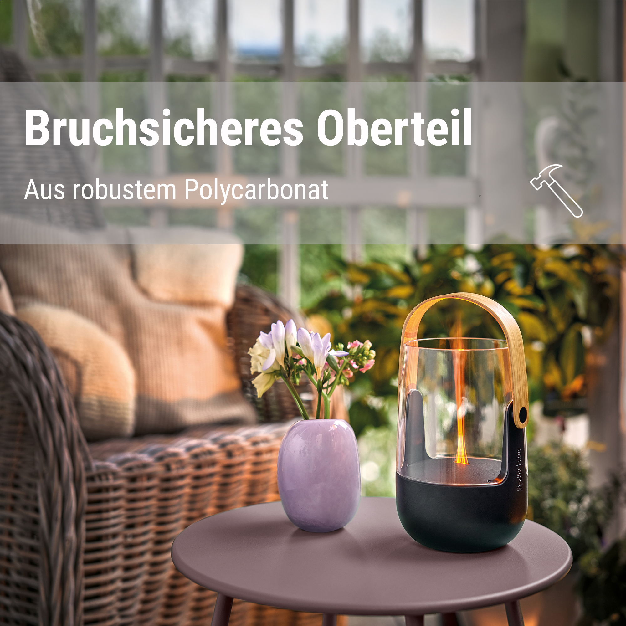 Brennende Laterne auf Tisch neben Vase mit Blumen und Rattansessel.