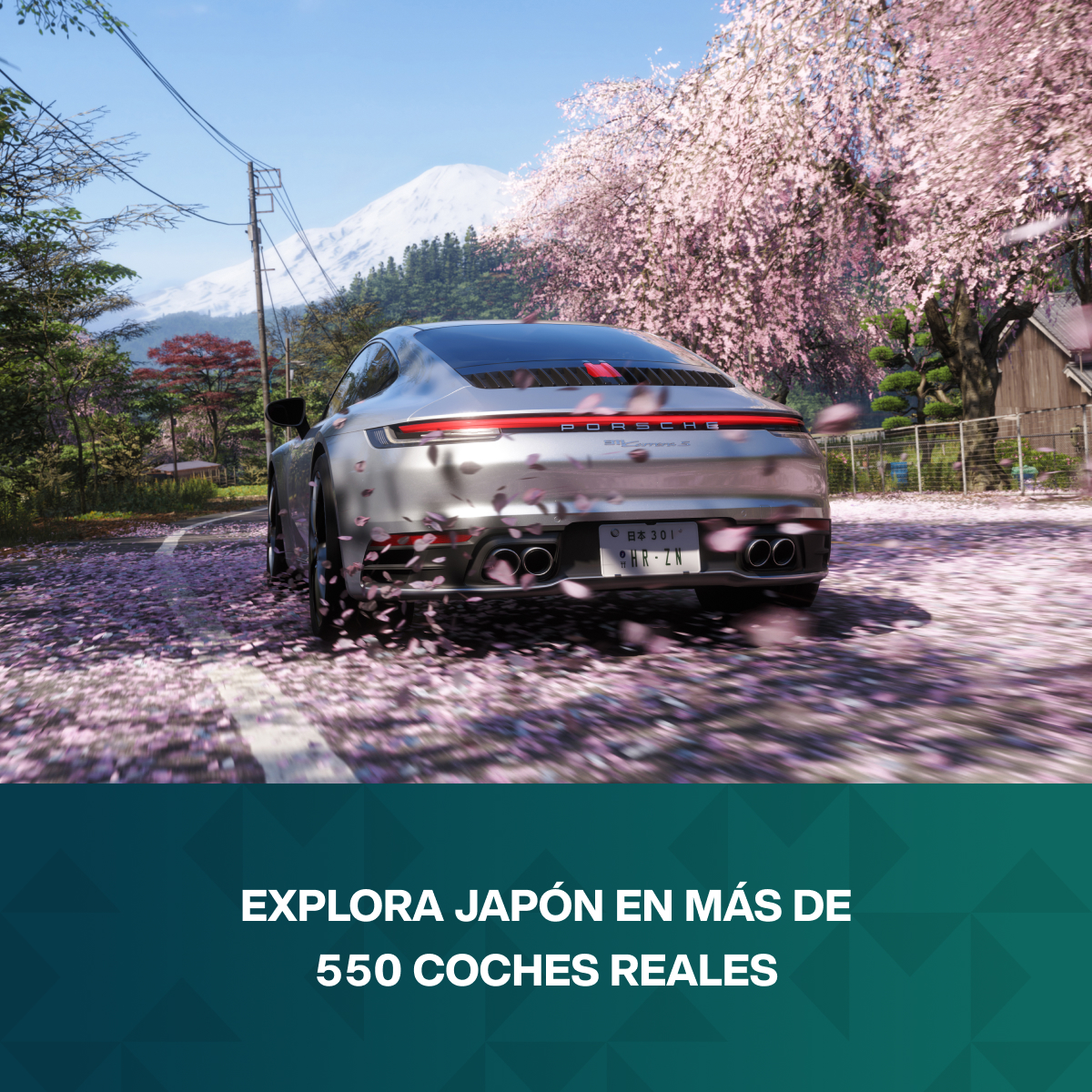 Porsche plateado circula por carretera con cerezos en flor y montañas nevadas.