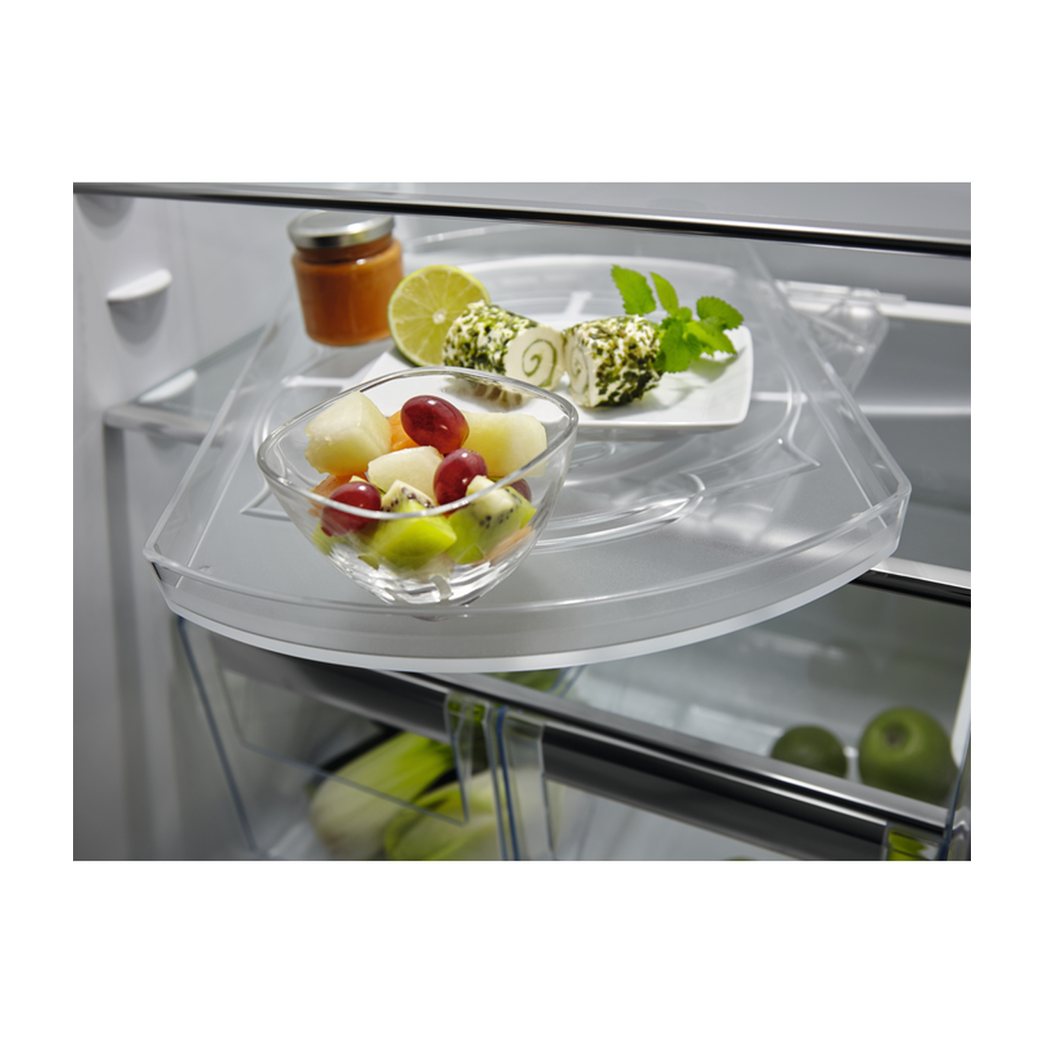 Macedonia in ciotola, rotolini di formaggio, lime e marmellata in frigo.
