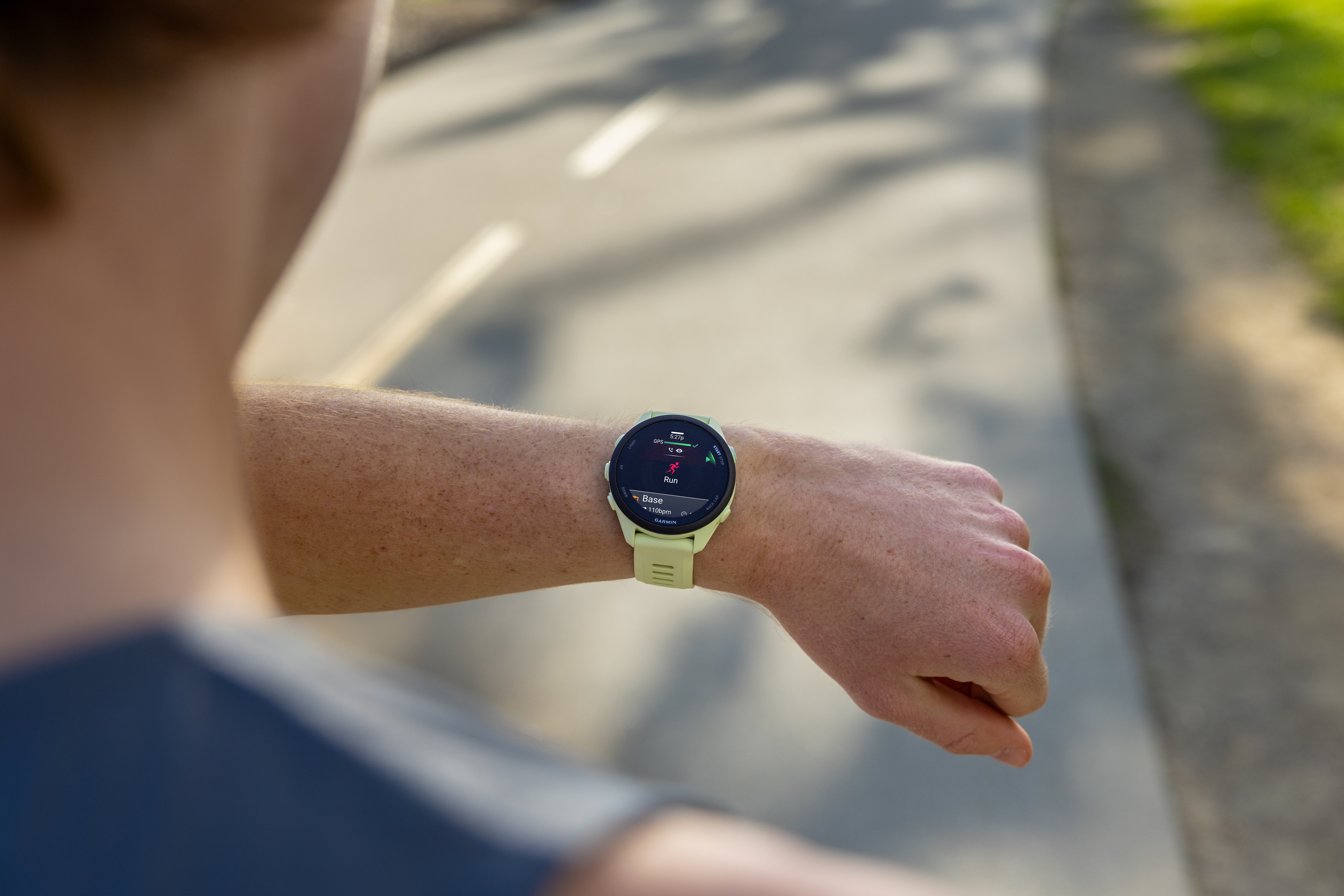 Eine Person mit einer hellgrünen Smartwatch am Handgelenk, die eine Laufaktivität anzeigt.