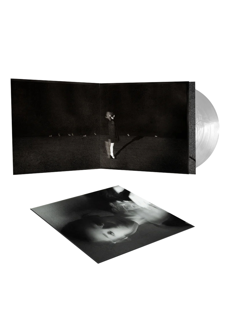Eine junge Frau steht in einem dunklen Raum, ein Vinyl-Album liegt daneben.