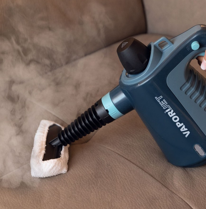 Parownica czyści brązową skórzaną kanapę z dużą ilością pary.