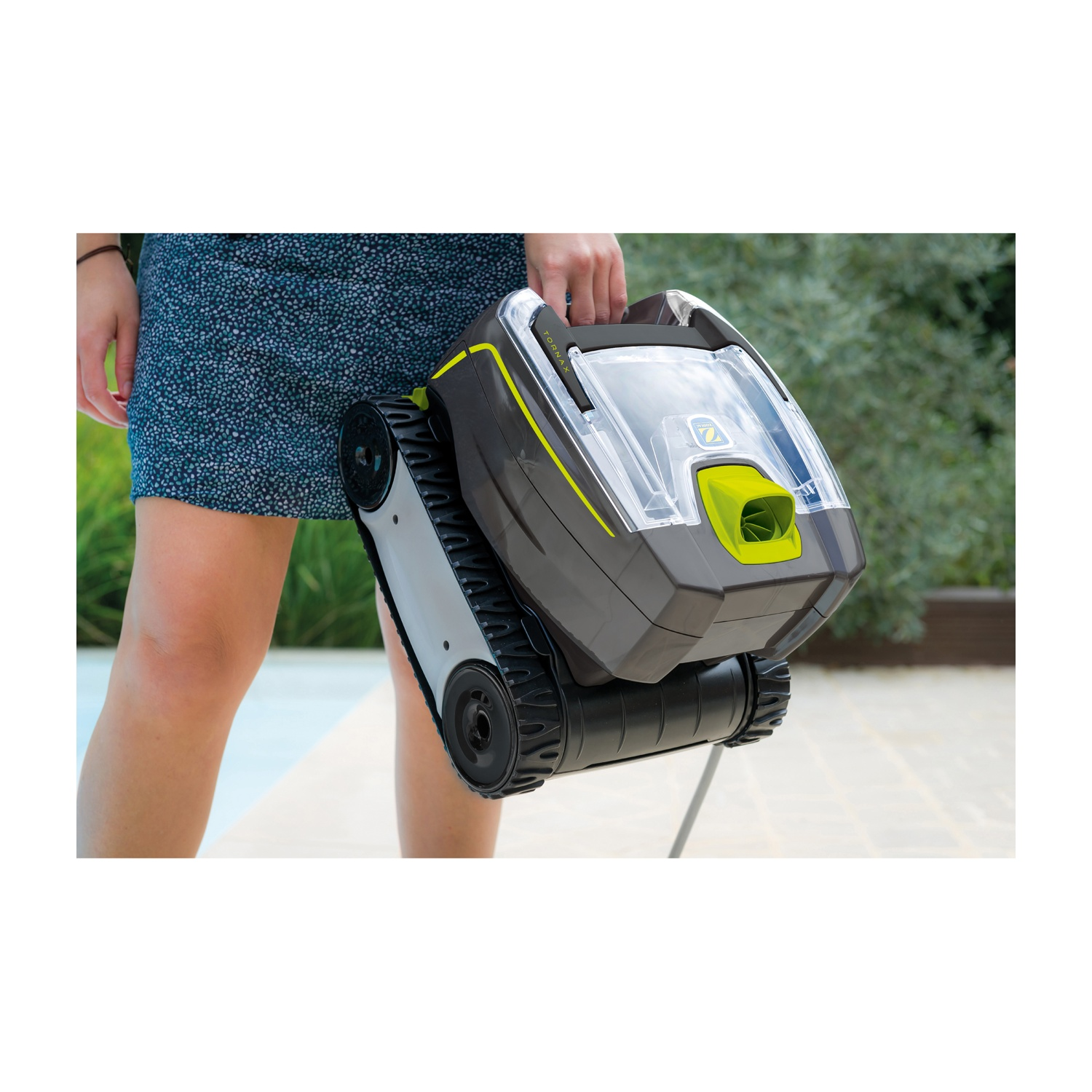 Una persona tiene un robot da piscina grigio e verde con cingoli all'aperto.