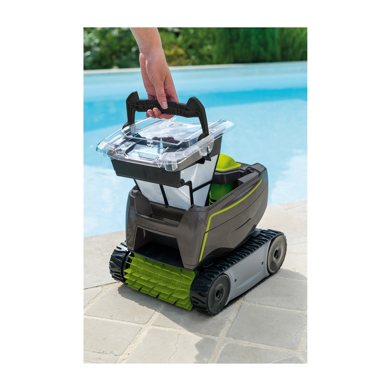 Una mano tiene un robot pulitore per piscine con spazzole verdi vicino a una piscina.
