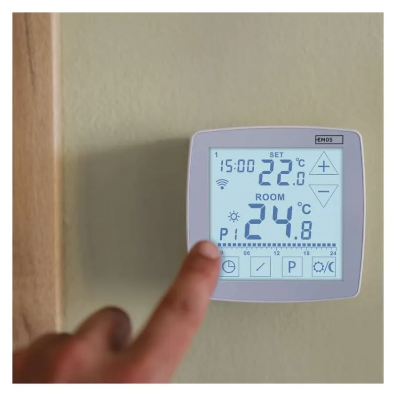 Egy ujj érint meg egy digitális termosztát kijelzőt, amely 22,0°C beállított és 24,8°C szobahőmérsékletet mutat.