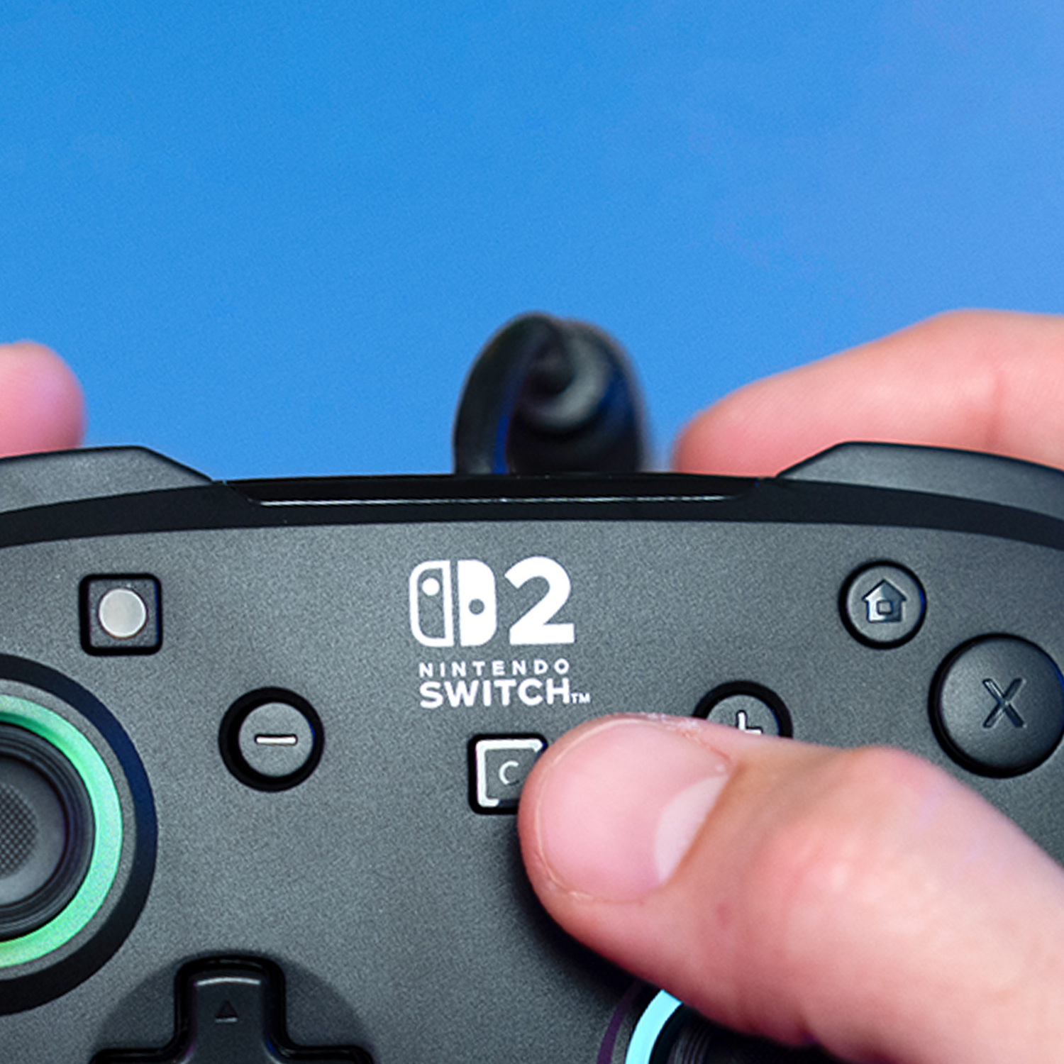 A finger presses the 'C' button on a black Nintendo Switch Pro 2 controller.