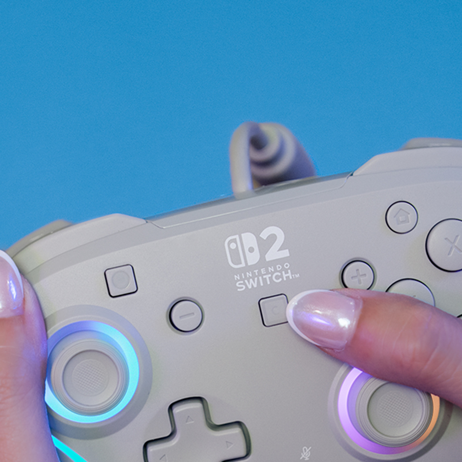 Hands hold a gray Nintendo Switch controller against a blue background.