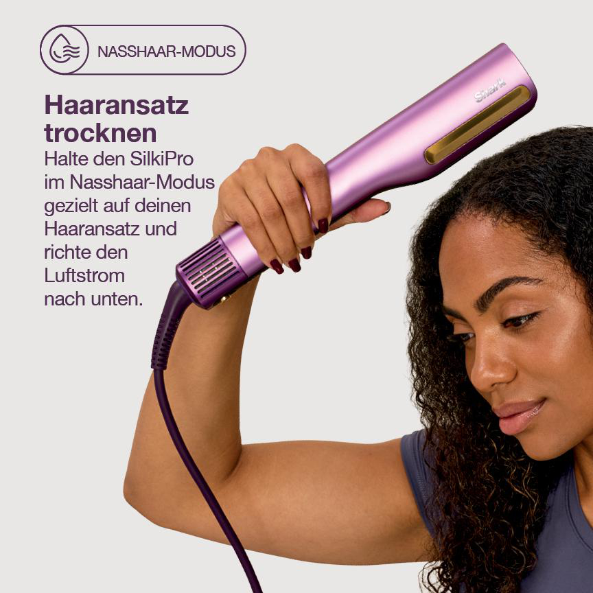 Eine Hand hält einen lila Haartrockner. Der Trockner richtet sich auf den Haaransatz einer Frau.