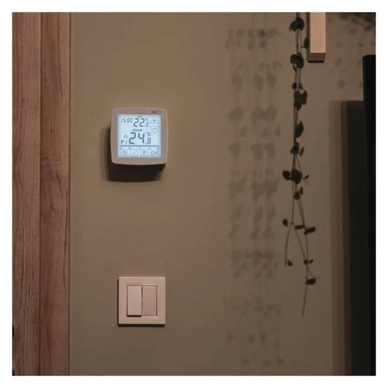 Digitális termosztát 22,0 és 24,8 fok kijelzéssel egy falon.