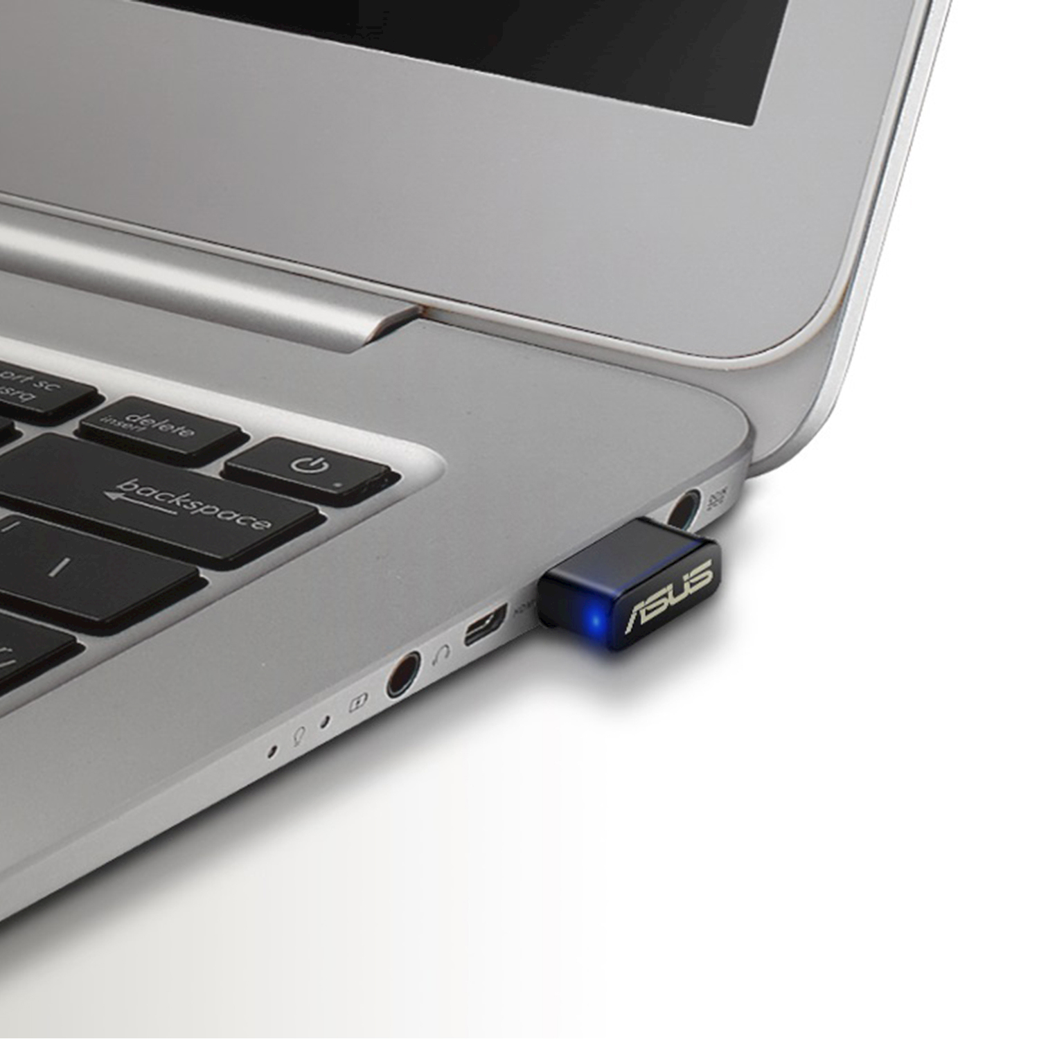 Un adattatore USB ASUS blu è collegato a un laptop accanto alla tastiera.