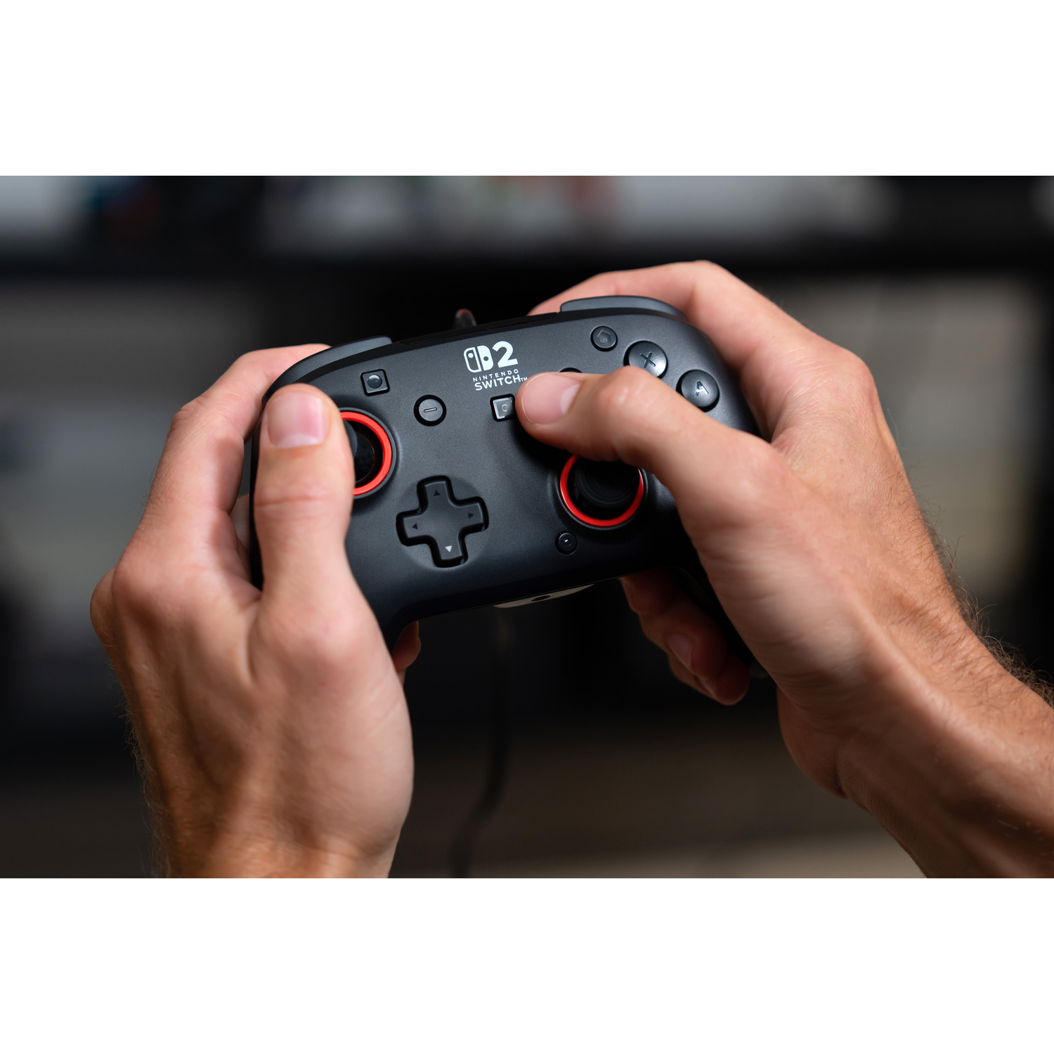 Hands holding a black Nintendo Switch controller with red accents.