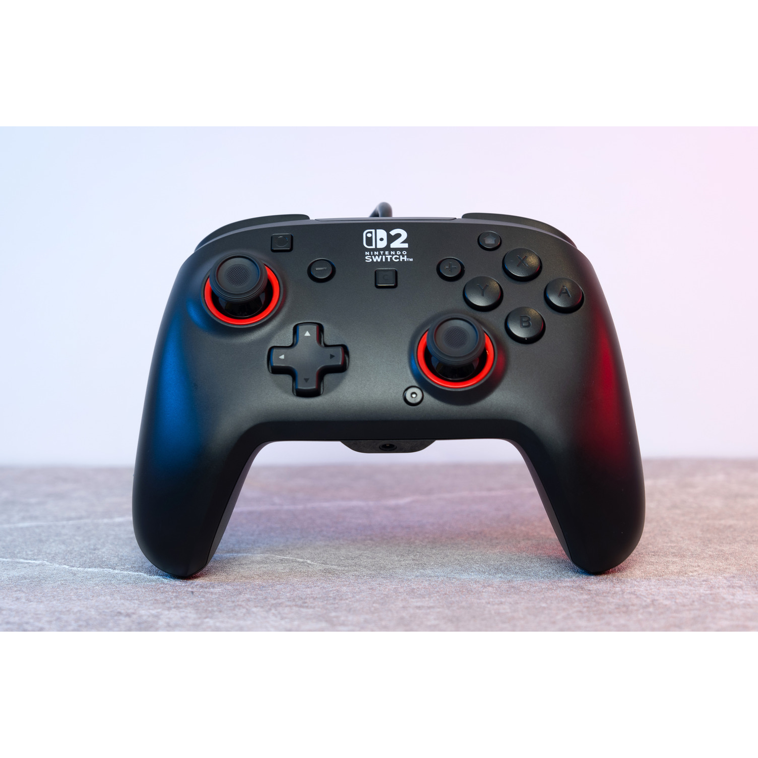 A black Nintendo Switch controller with red accents on a stone surface.