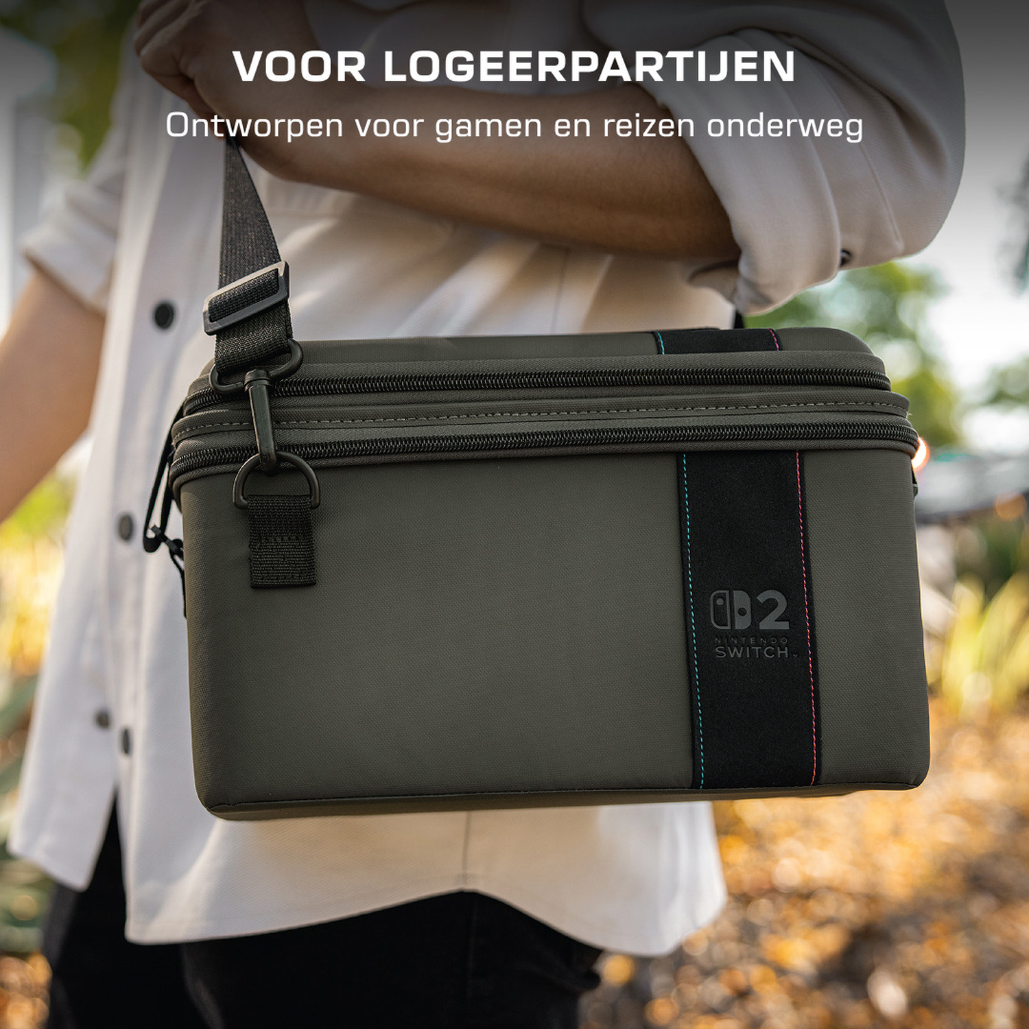 Een olijfgroene Nintendo Switch tas met draagband wordt door een persoon gedragen.