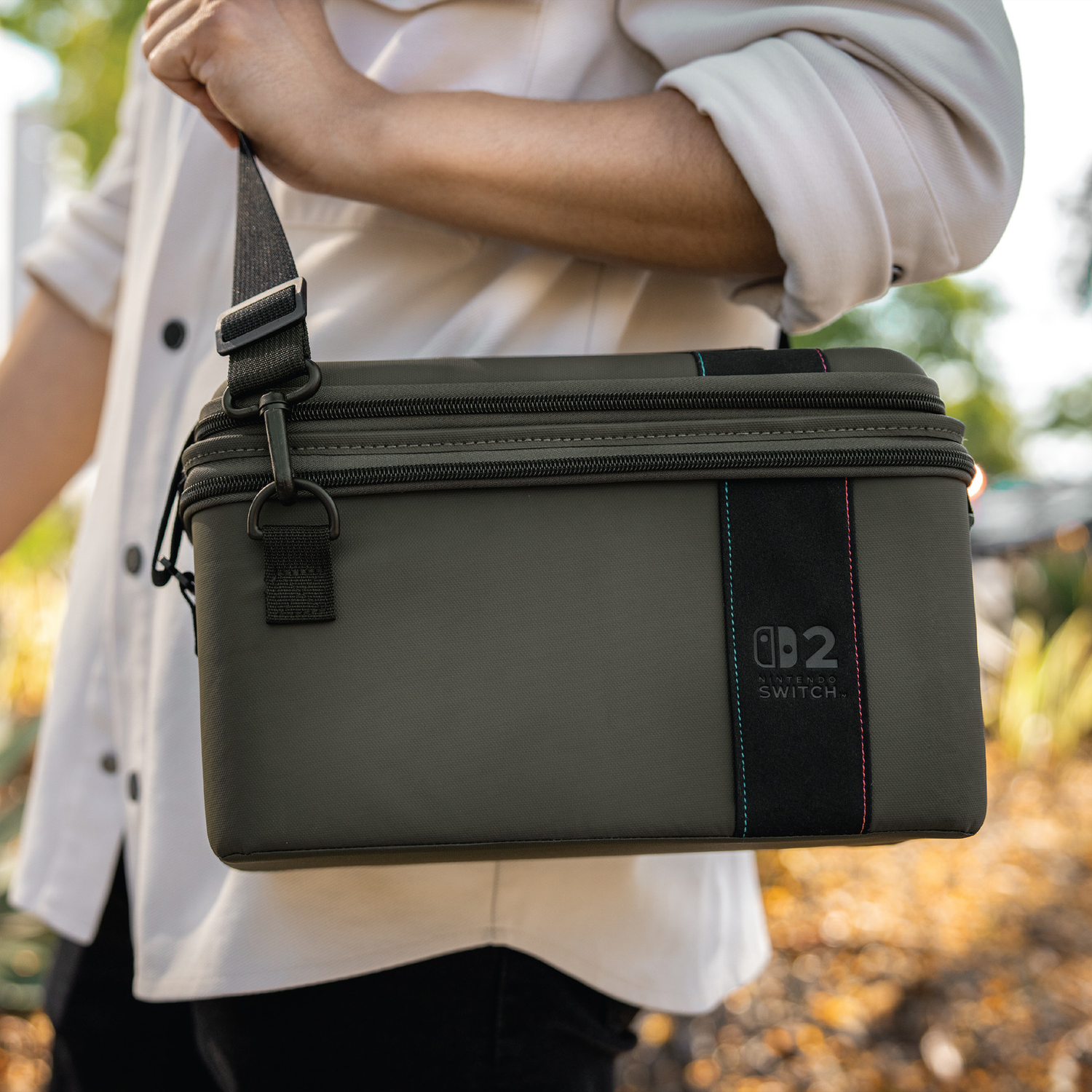 Groene Nintendo Switch tas met zwarte band gedragen door persoon in licht hemd.