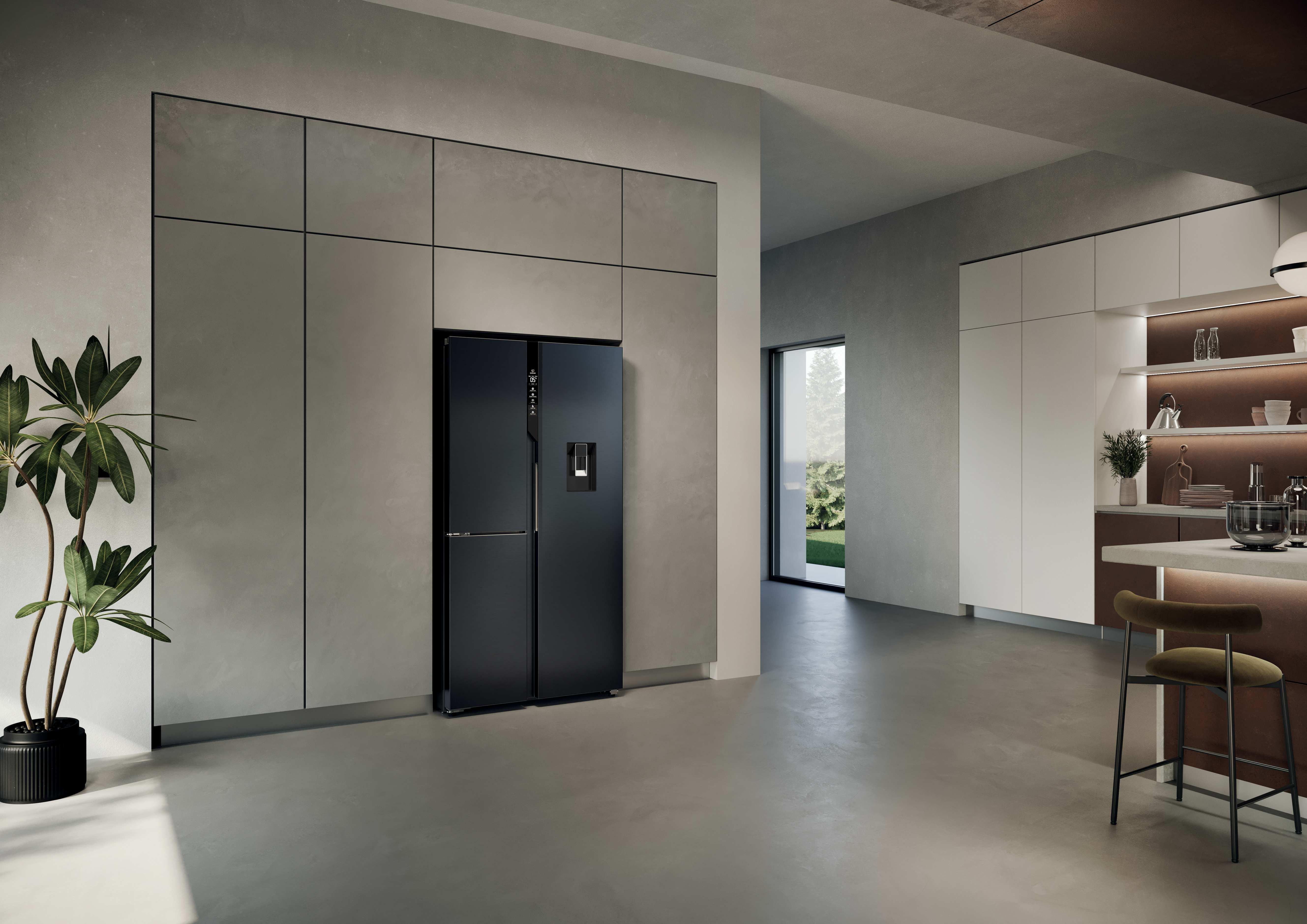 Ein moderner schwarzer Kühlschrank steht in einer Küche mit Betonwänden.