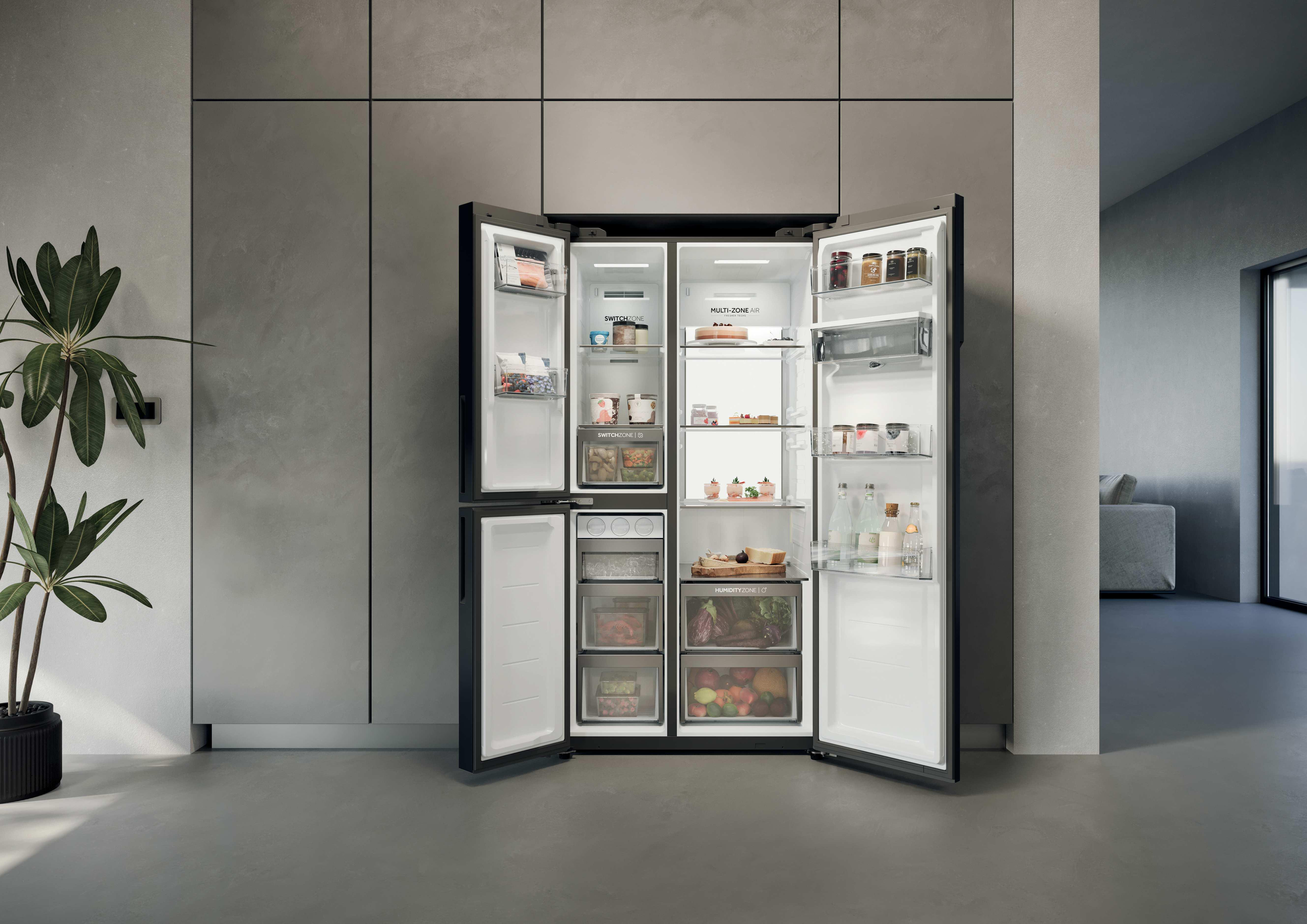 Offener Kühlschrank mit Lebensmitteln und eine Topfpflanze daneben.