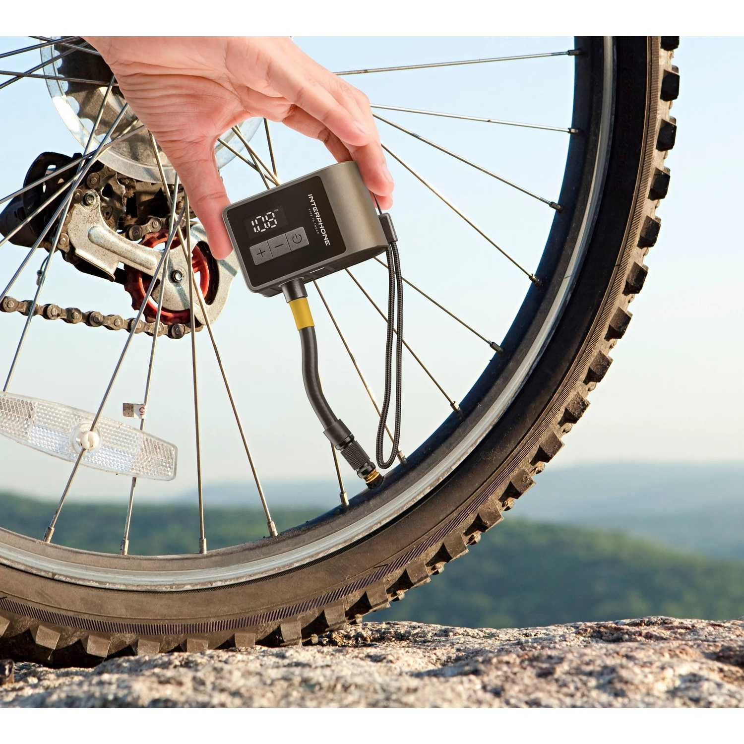 Una persona usa un dispositivo digitale per gonfiare uno pneumatico da bicicletta all'aperto.
